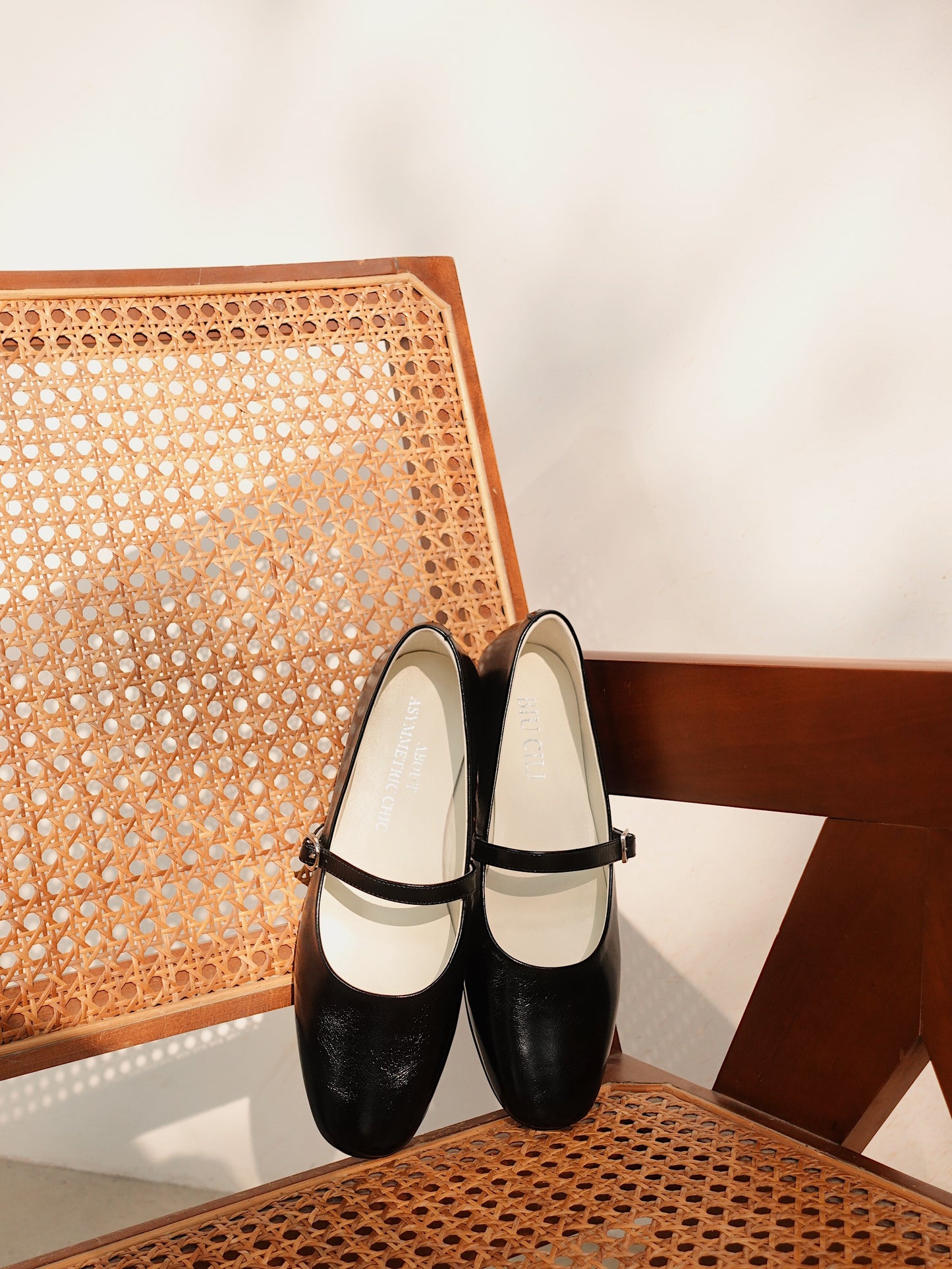 A pair of classic black mary jane flats on a neutral color chic chair