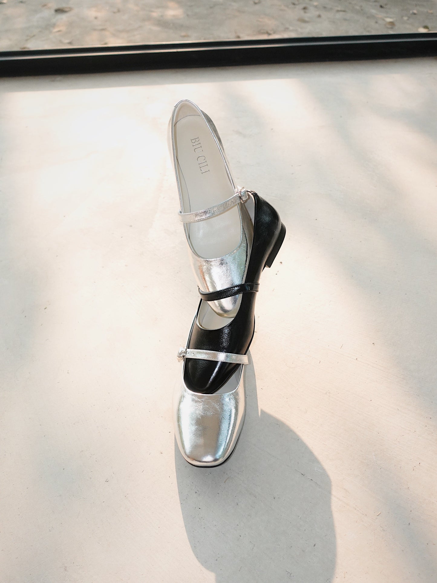 Three mary jane flats in black and silver stacking together