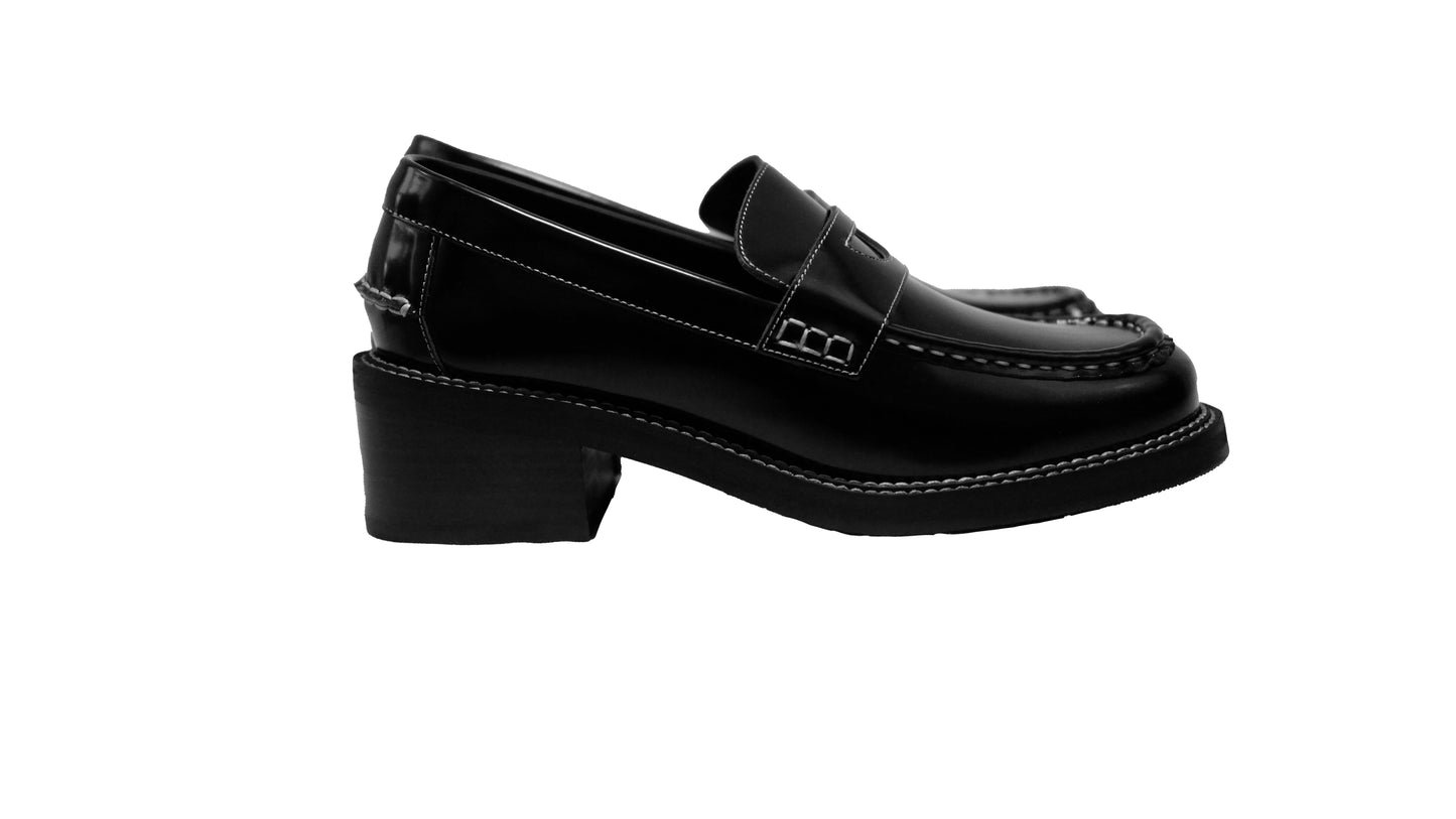 Side view of a pair of black leather loafer heels with asymmetric details for women.