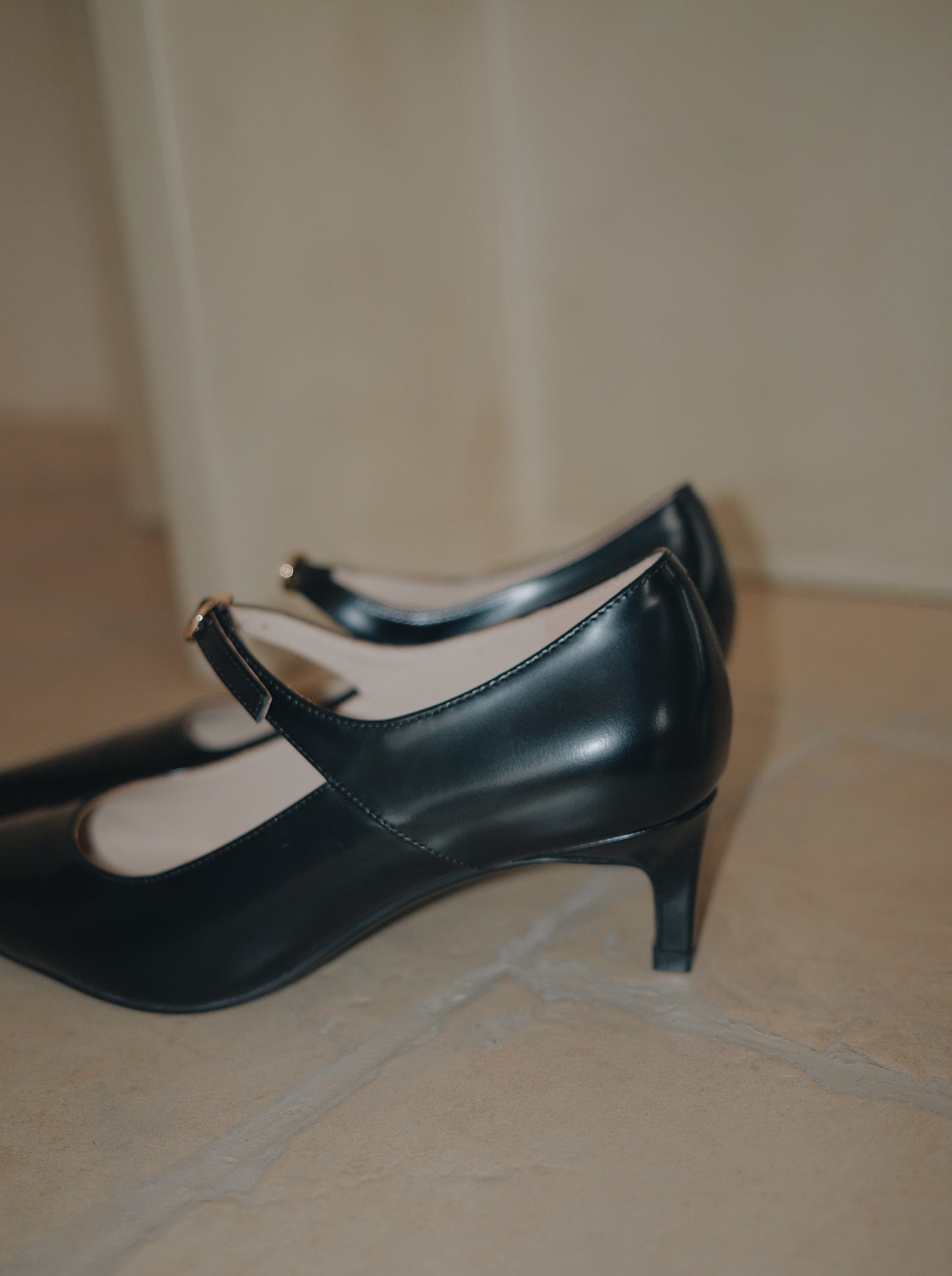 Black pointed-toe Mary Jane heel with metal buckle displayed sideways showing the details of the heel