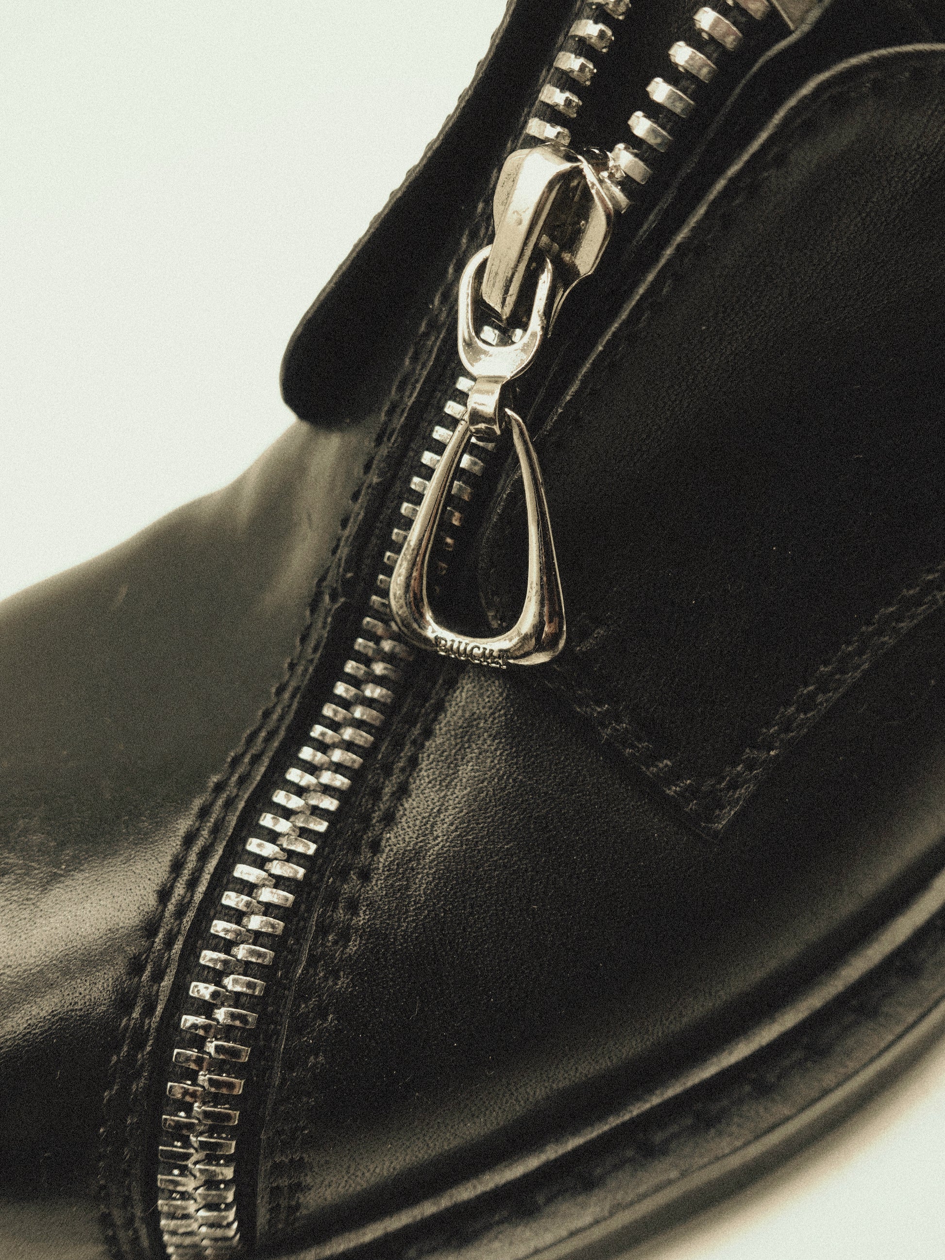 Black asymmetric leather loafers with curved zipper detail and rounded toe