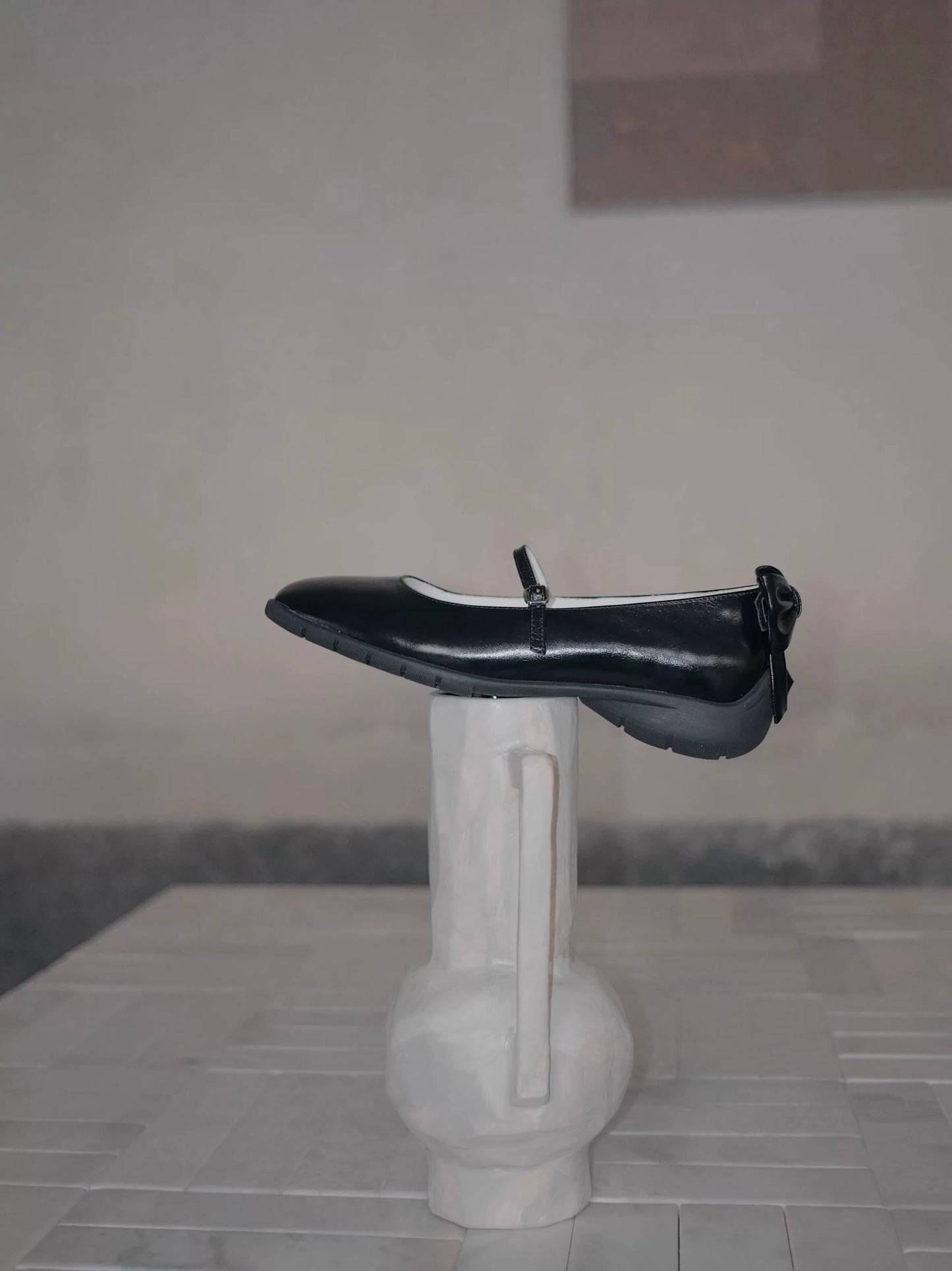 Showing the side view of the black leather mary jane flats with bow at the back, and the sporty sole