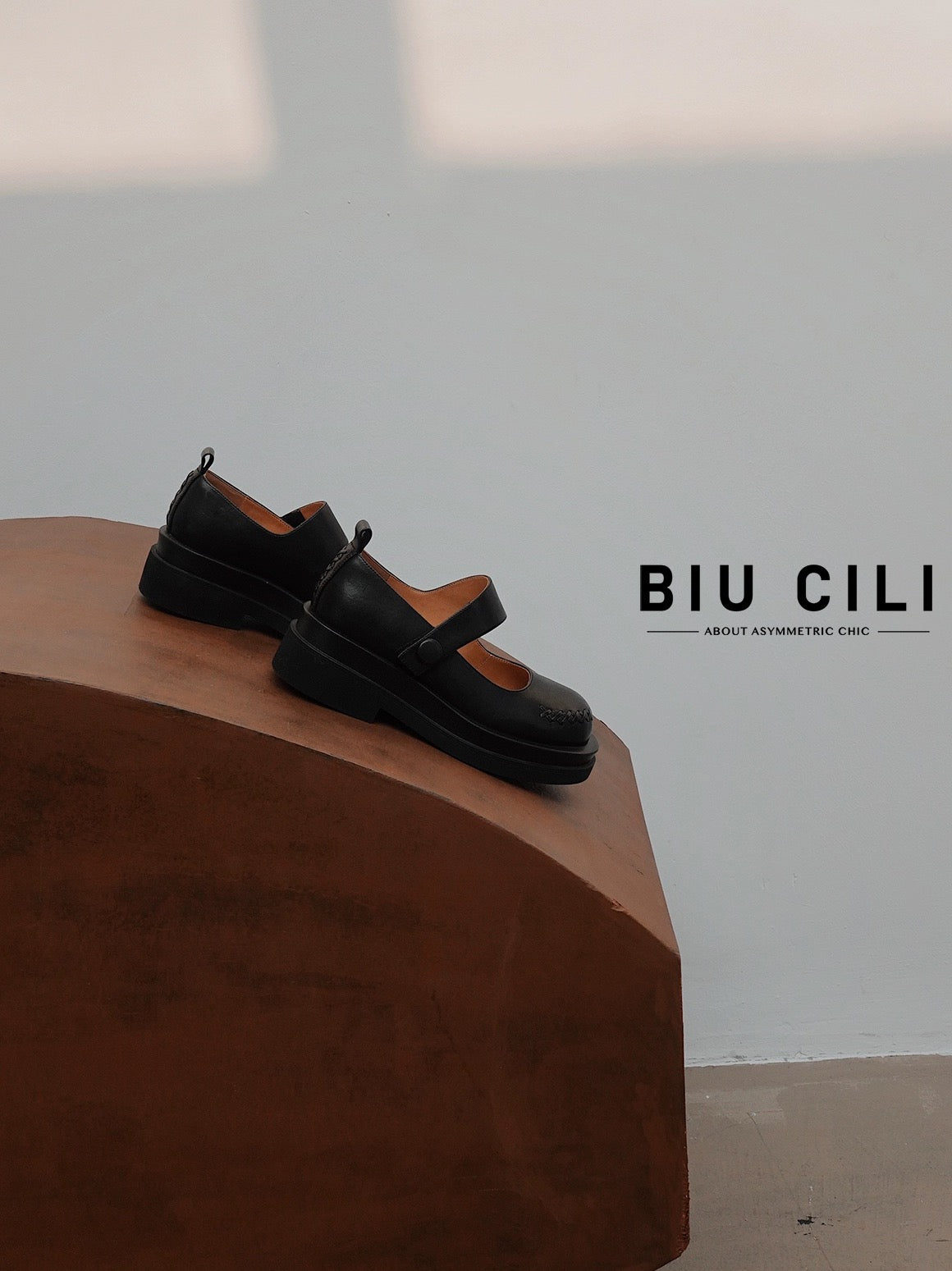 Black platform Mary Jane shoes with wide strap and low block heel, displayed on a wooden surface