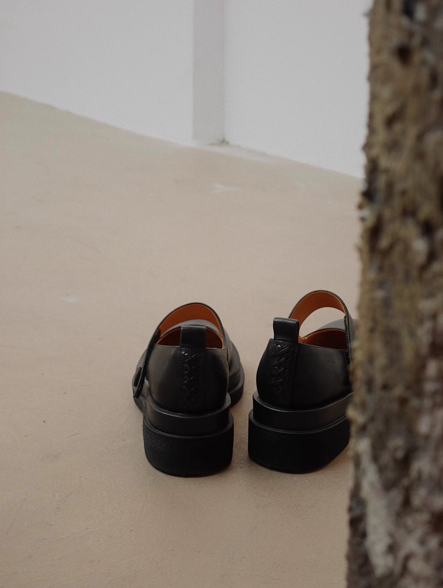 Black platform Mary Jane shoes with wide strap and low block heel, displayed on a textured concrete floor