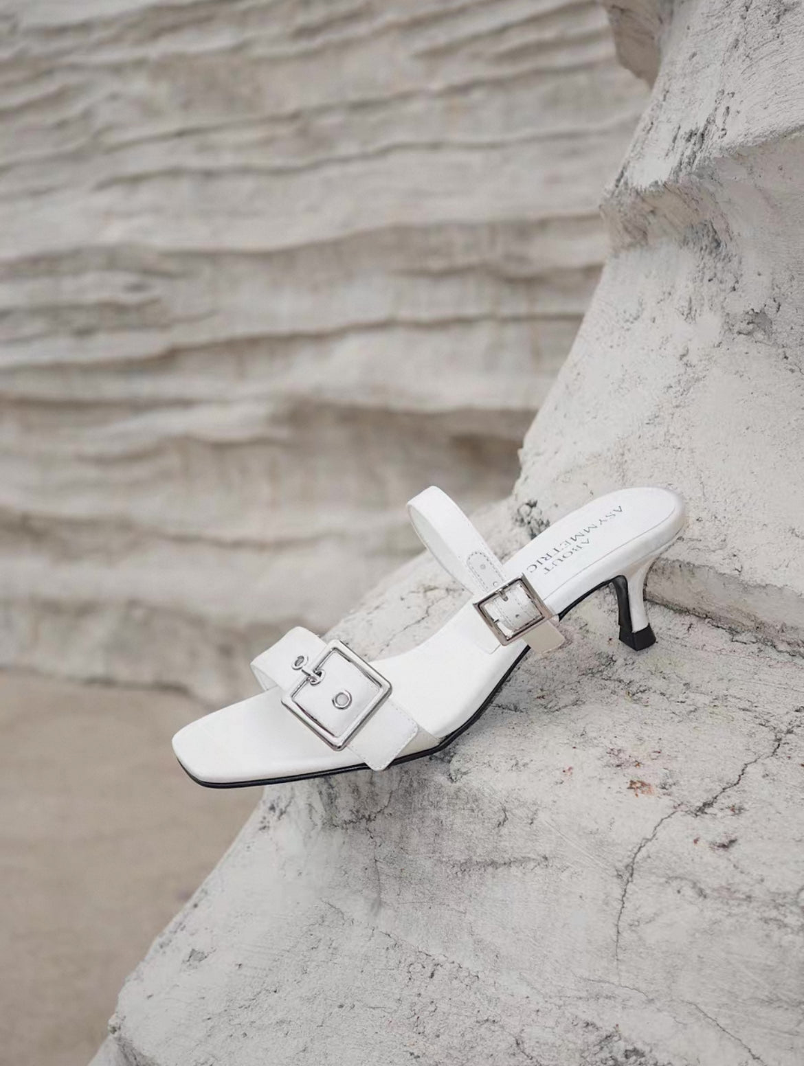 A mid heel sandal with two thick white silk straps and shiny silver buckle - side view