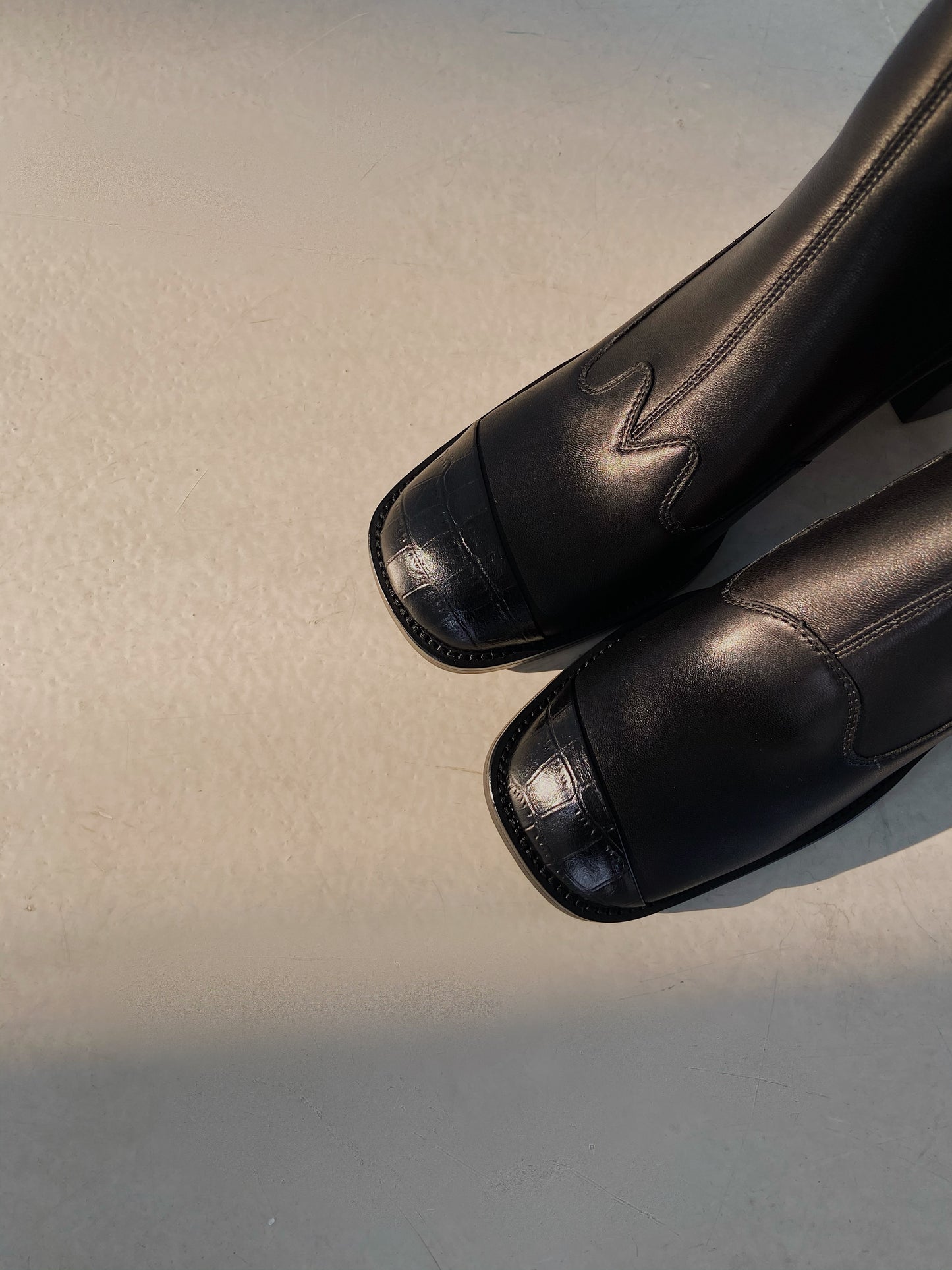 Upper view of a pair of women's black leather square-toe ankle boots with block heels