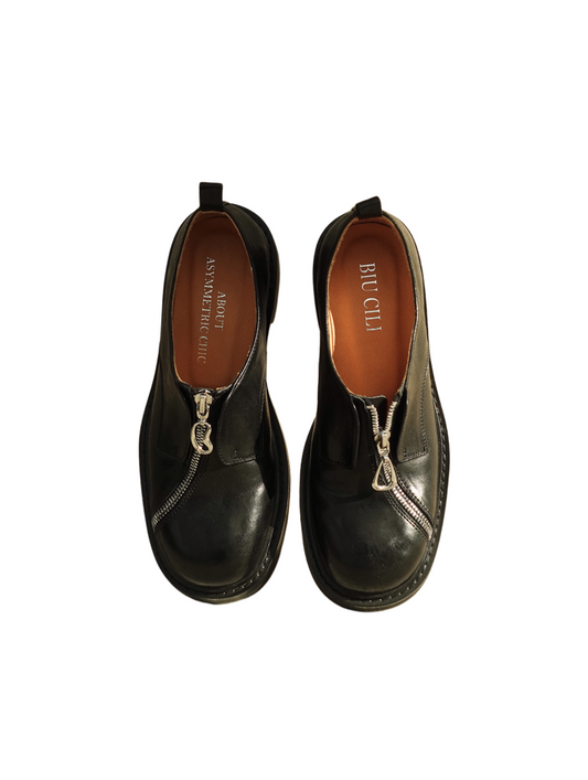 Black asymmetric leather loafers with curved zipper detail and rounded toe