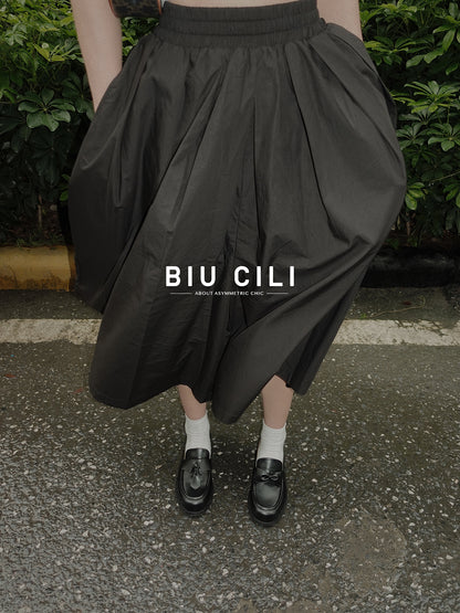 Women wearing a pair of black leather loafers featuring asymmetric tie and bow details, crafted in matte calfskin with low heel and soft structure, pairing with a black dress, standing on the street