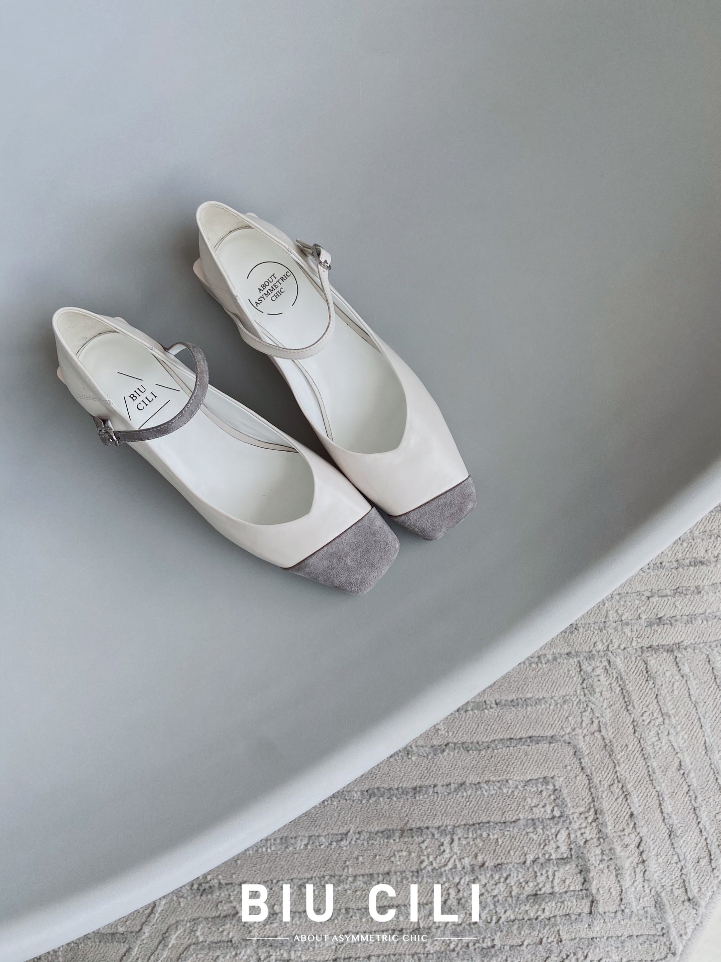 Top view of White leather square-toe Mary Jane heels with asymmetric ankle straps and light grey suede toe caps
