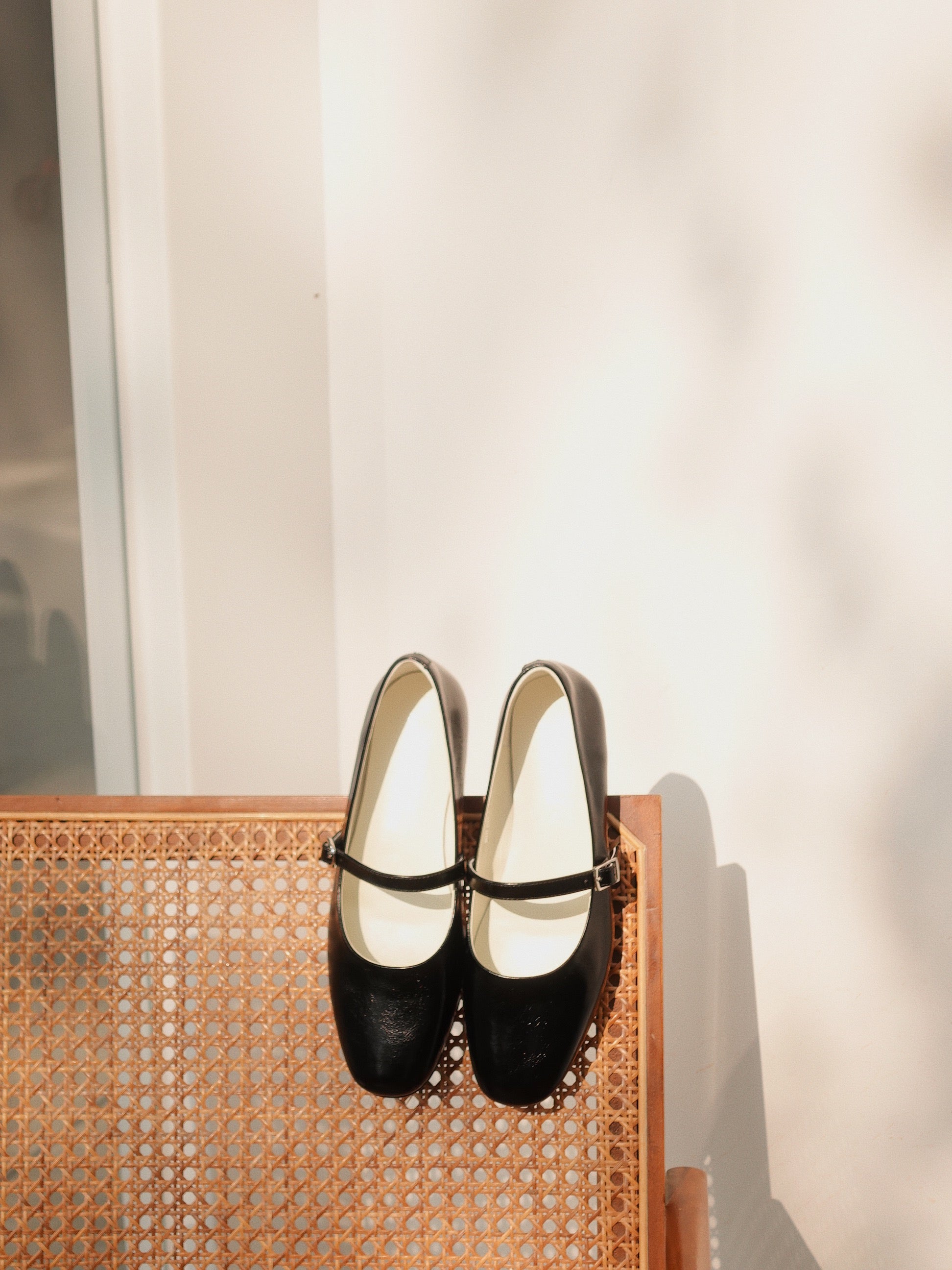 A pair of classic black mary jane flats on a neutral color chair