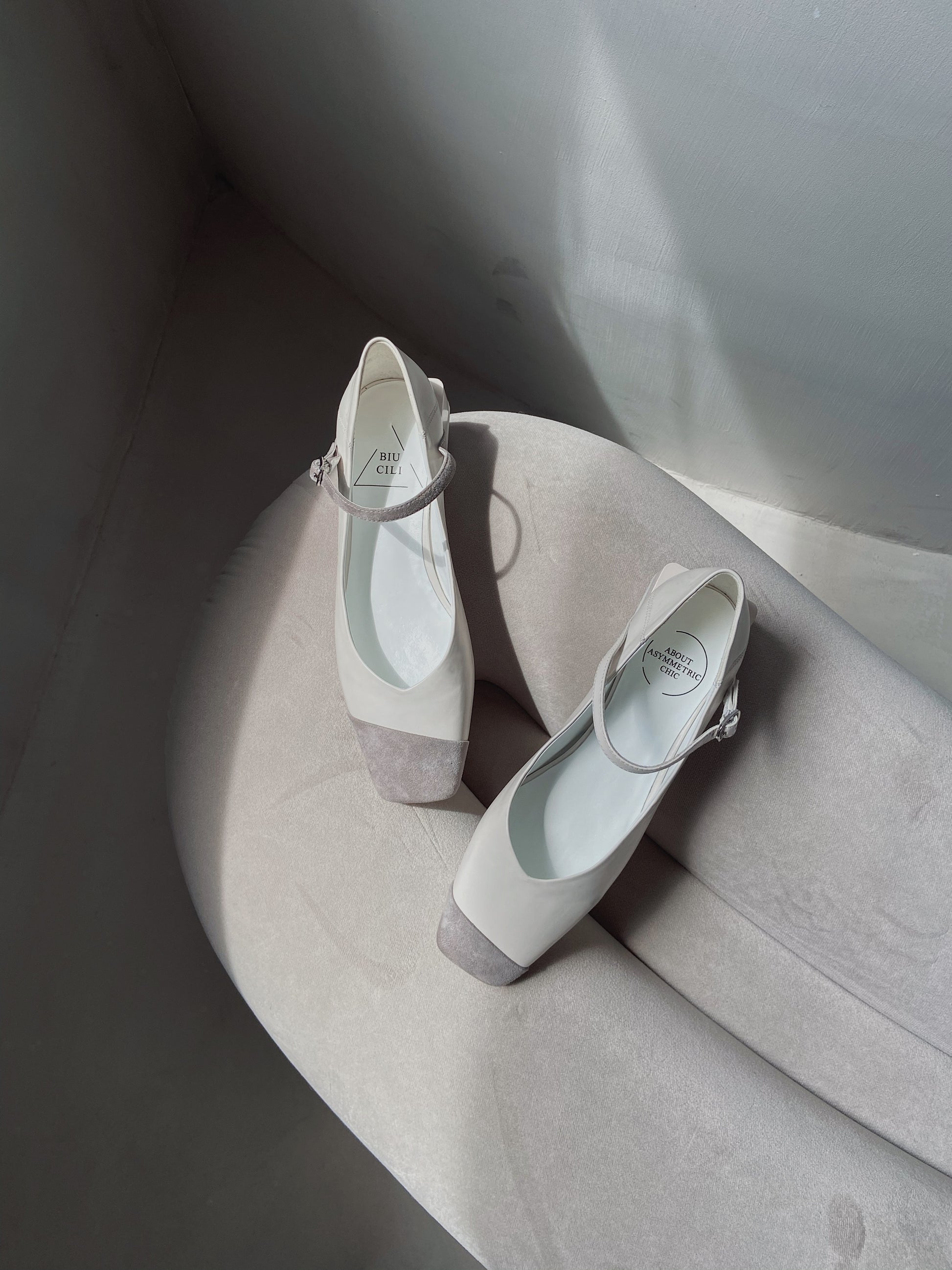 White leather square-toe Mary Jane heels with asymmetric ankle straps and light grey suede toe caps
