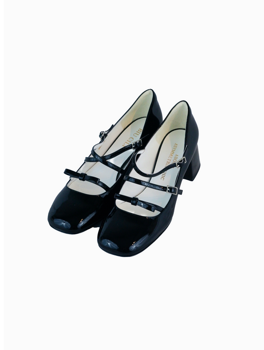 Black patent leather Mary Jane heels with triple straps, block heel, and bow detail.