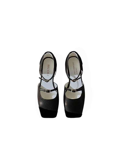 A pair of black leather mary jane flats with straps and asymmetric velvet details at toe front, placed on a white background