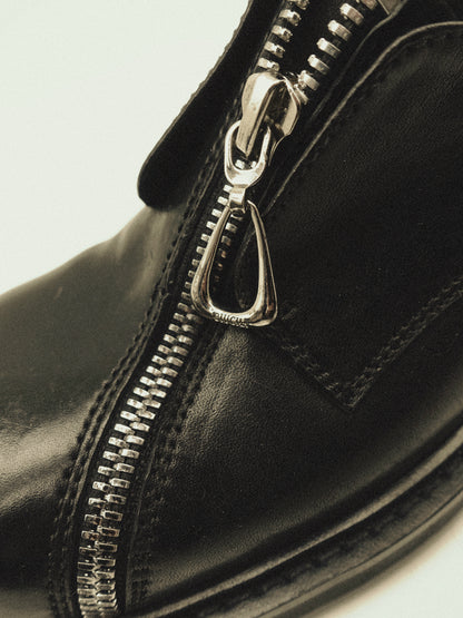 Black asymmetric leather loafers with curved zipper detail and rounded toe