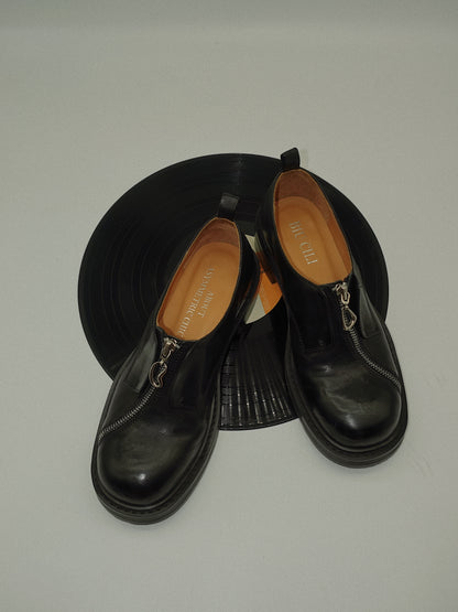Black asymmetric leather loafers with curved zipper detail and rounded toe