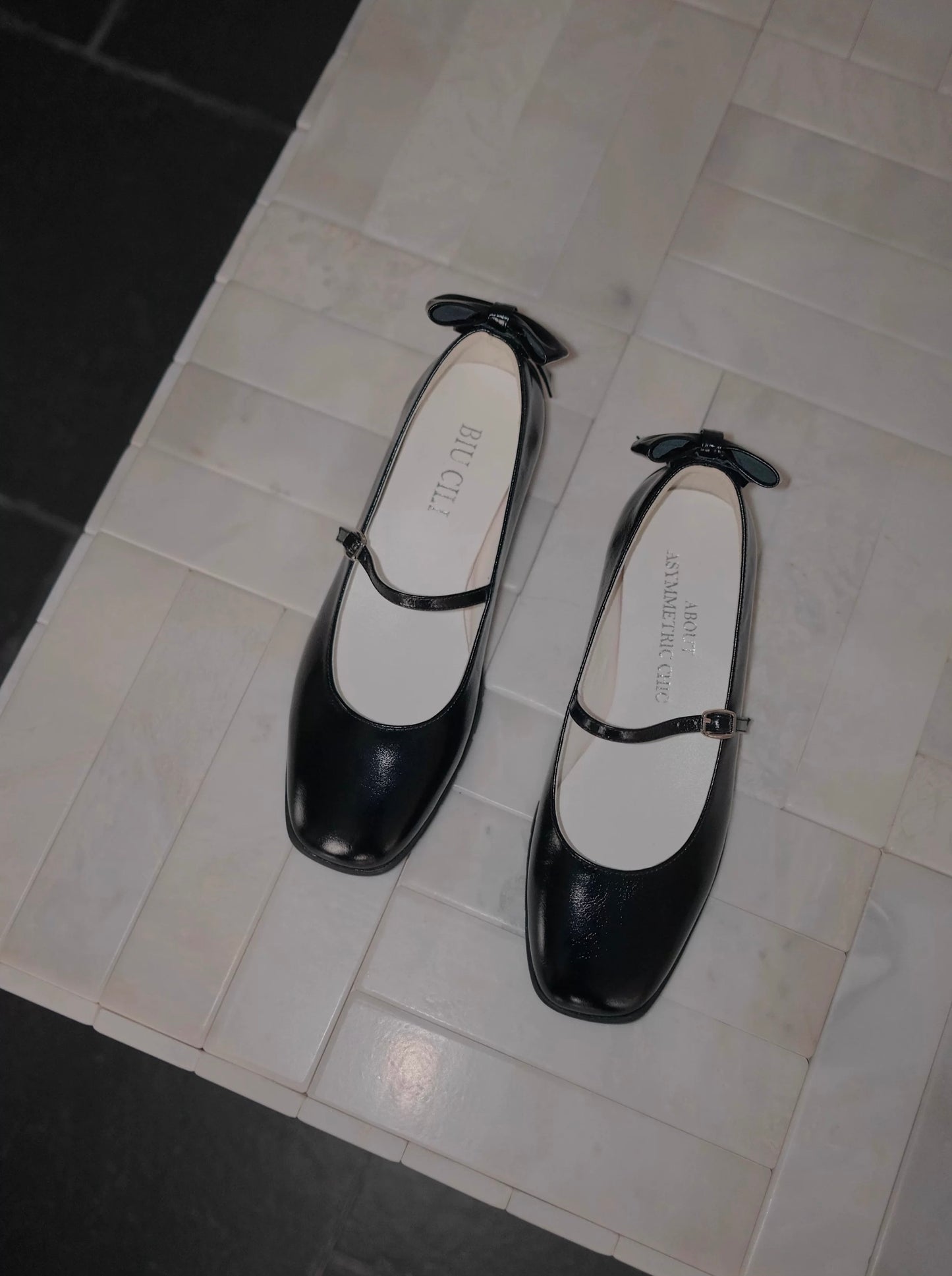 Women's black leather Sporty Mary Jane shoes in classic and chic black with back bow place on the floor - top view