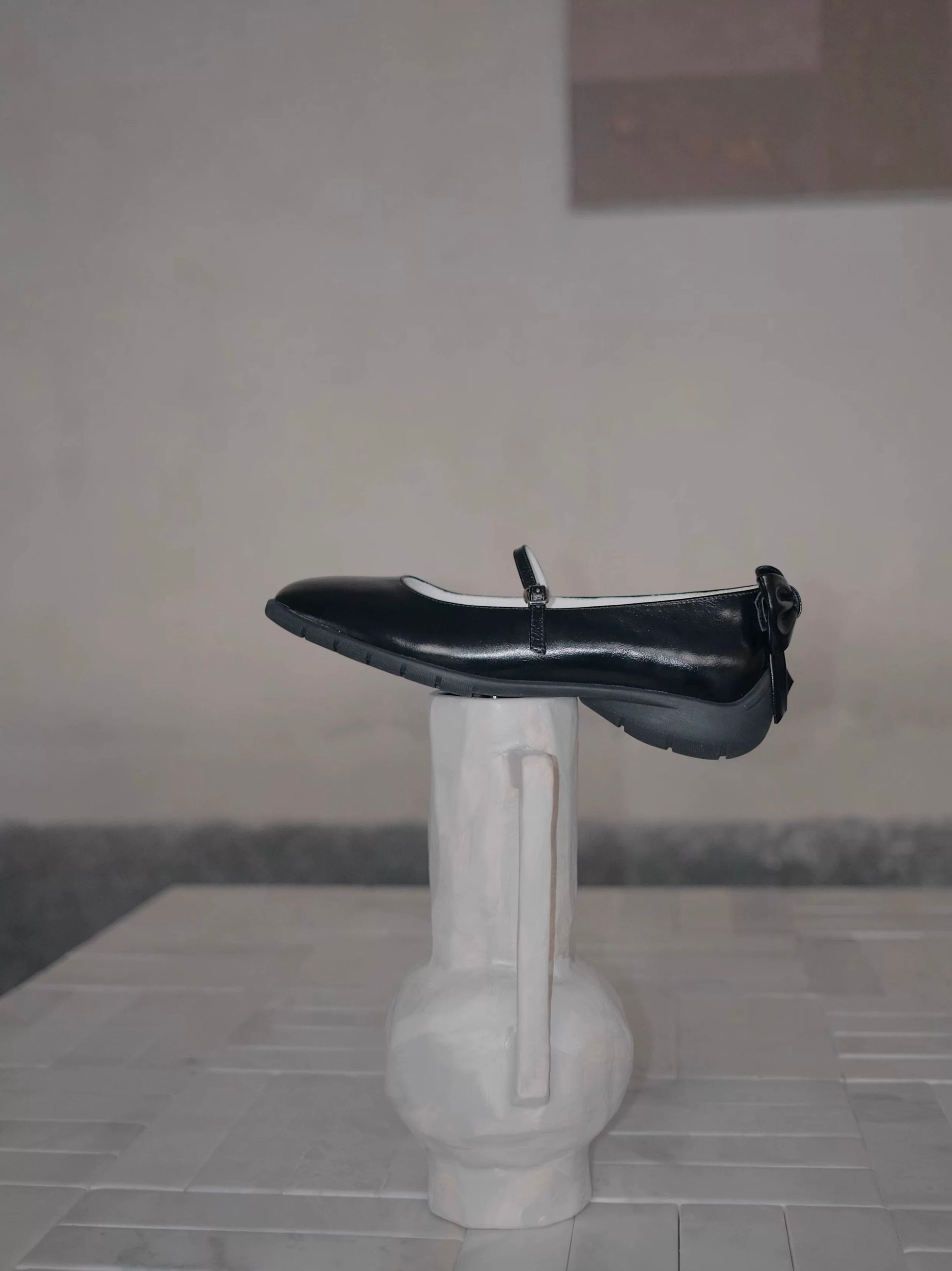 Showing the side view of the black leather mary jane flats with bow at the back, and the sporty sole