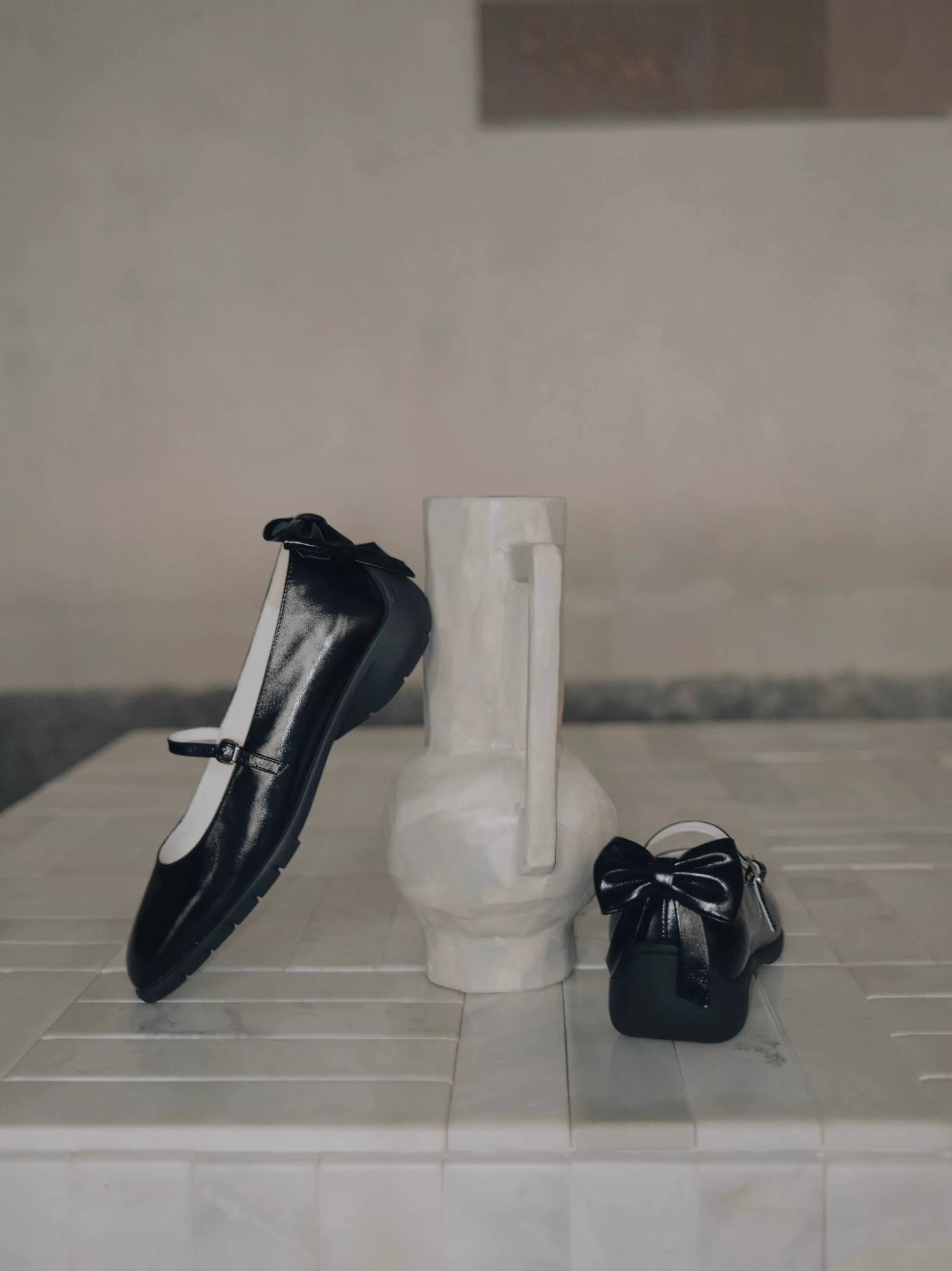 Showing the side view and the back view of the black leather mary jane flats with back bow details