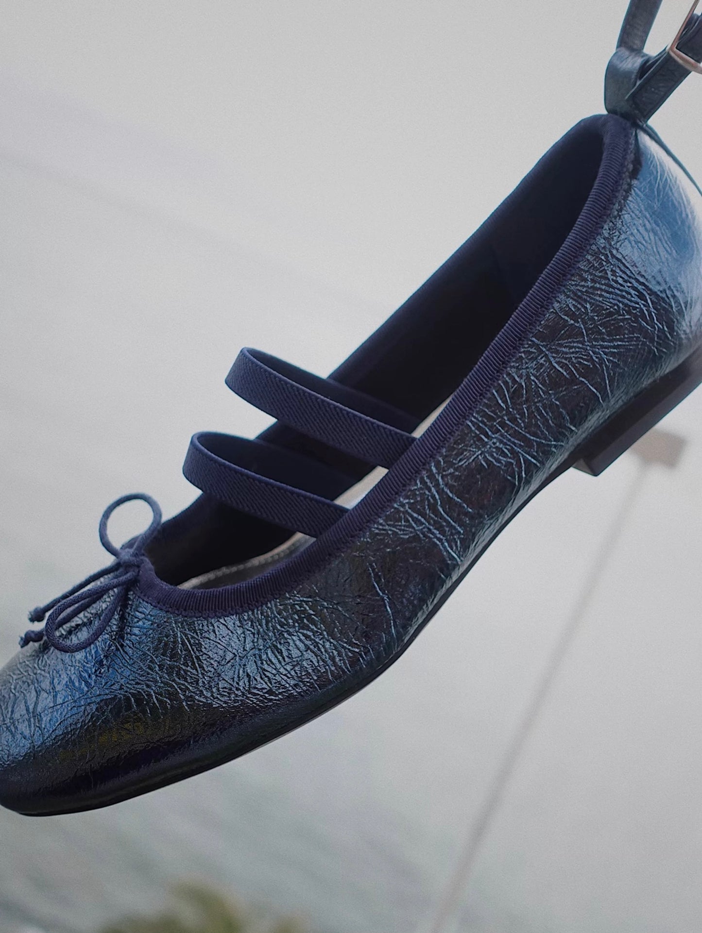 Closed Side view of navy metallic leather Mary Jane ballet flats with asymmetrical cross straps
