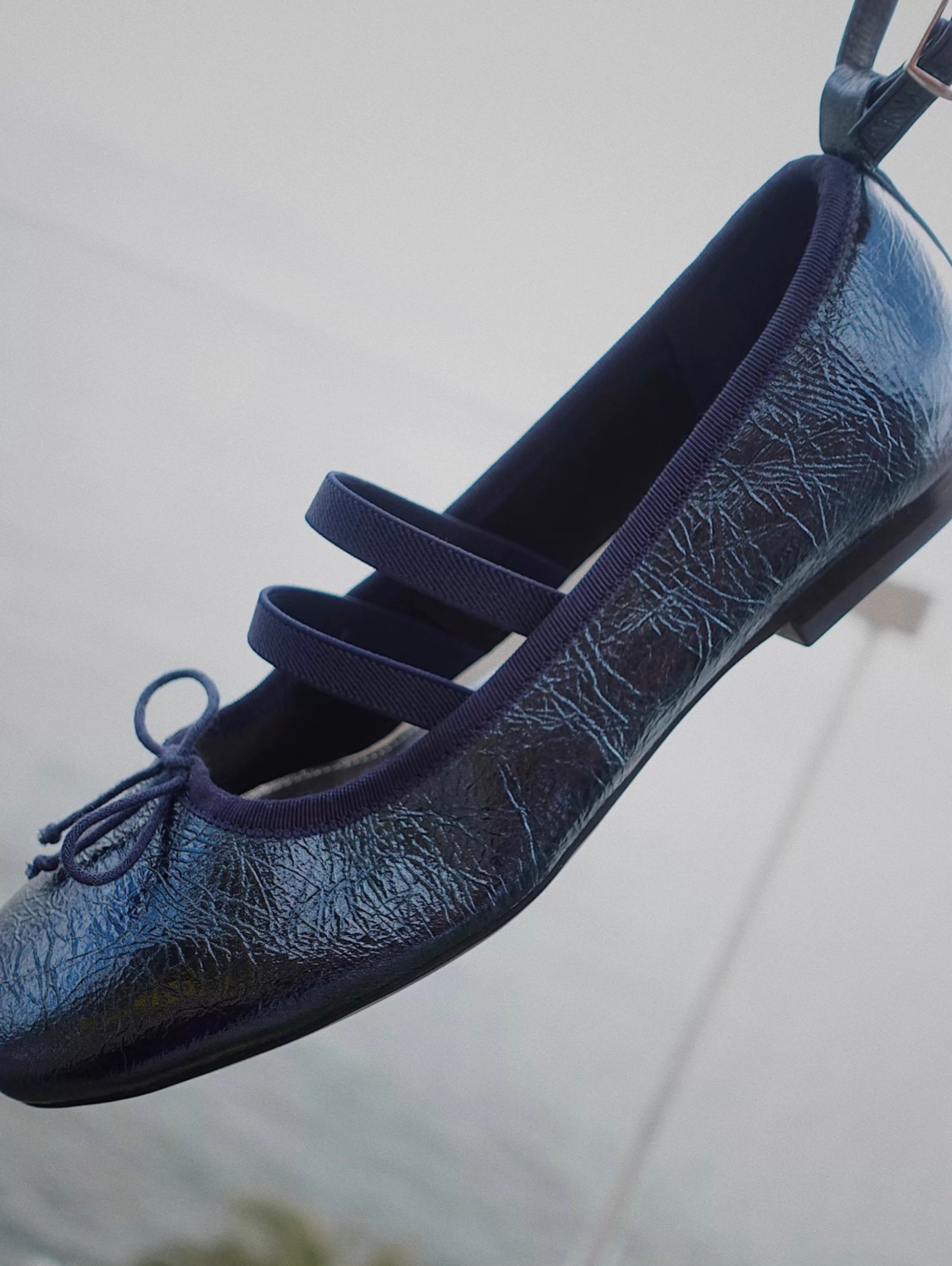 Closed Side view of navy metallic leather Mary Jane ballet flats with asymmetrical cross straps
