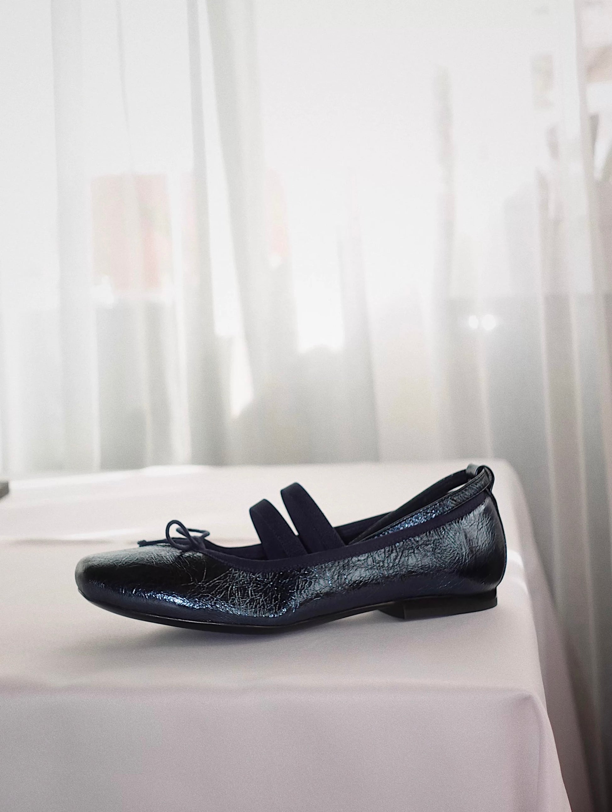 Side view of navy metallic leather Mary Jane ballet flats with asymmetrical cross straps
