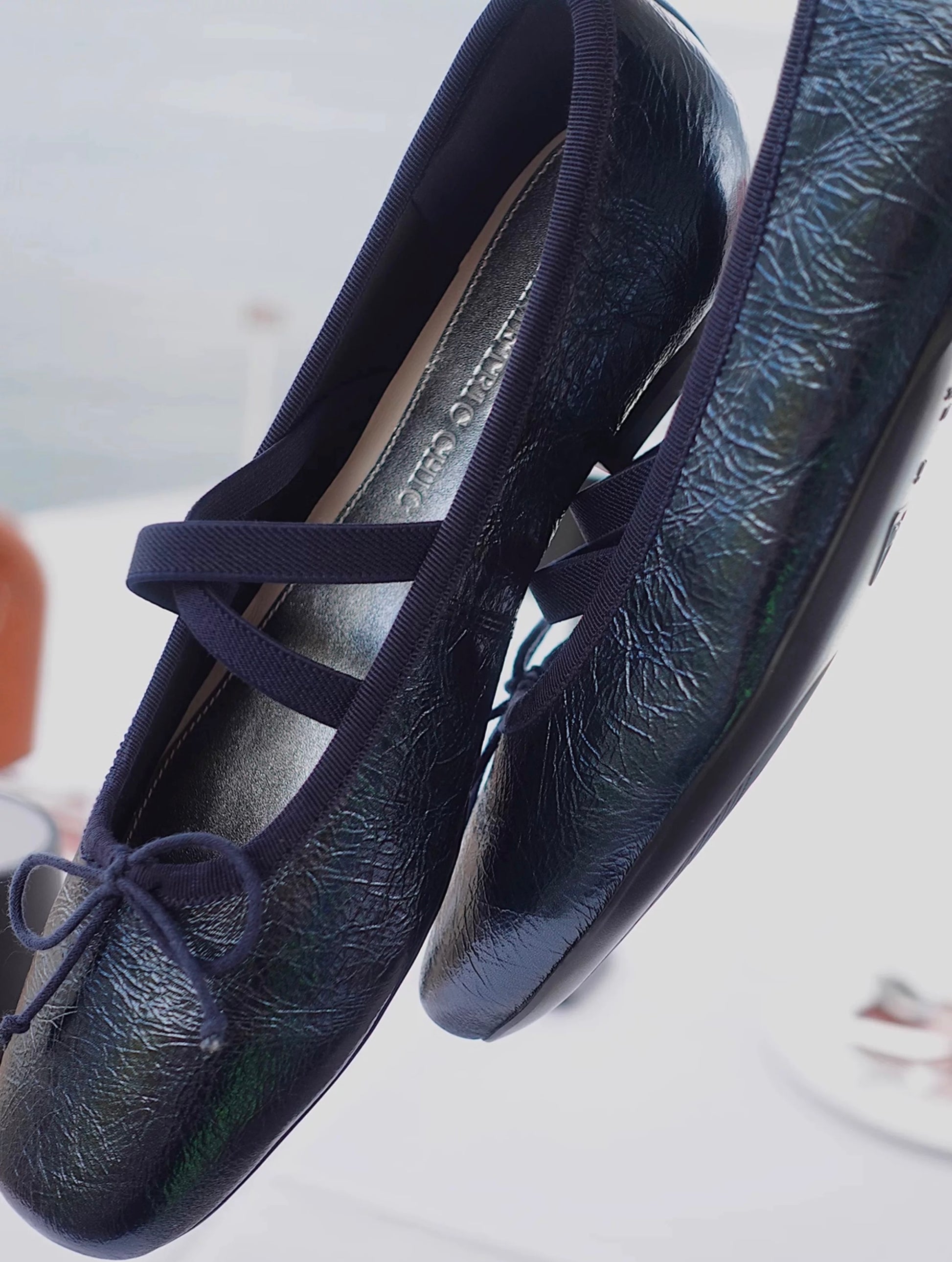 Side view of navy metallic leather Mary Jane ballet flats with asymmetrical cross straps