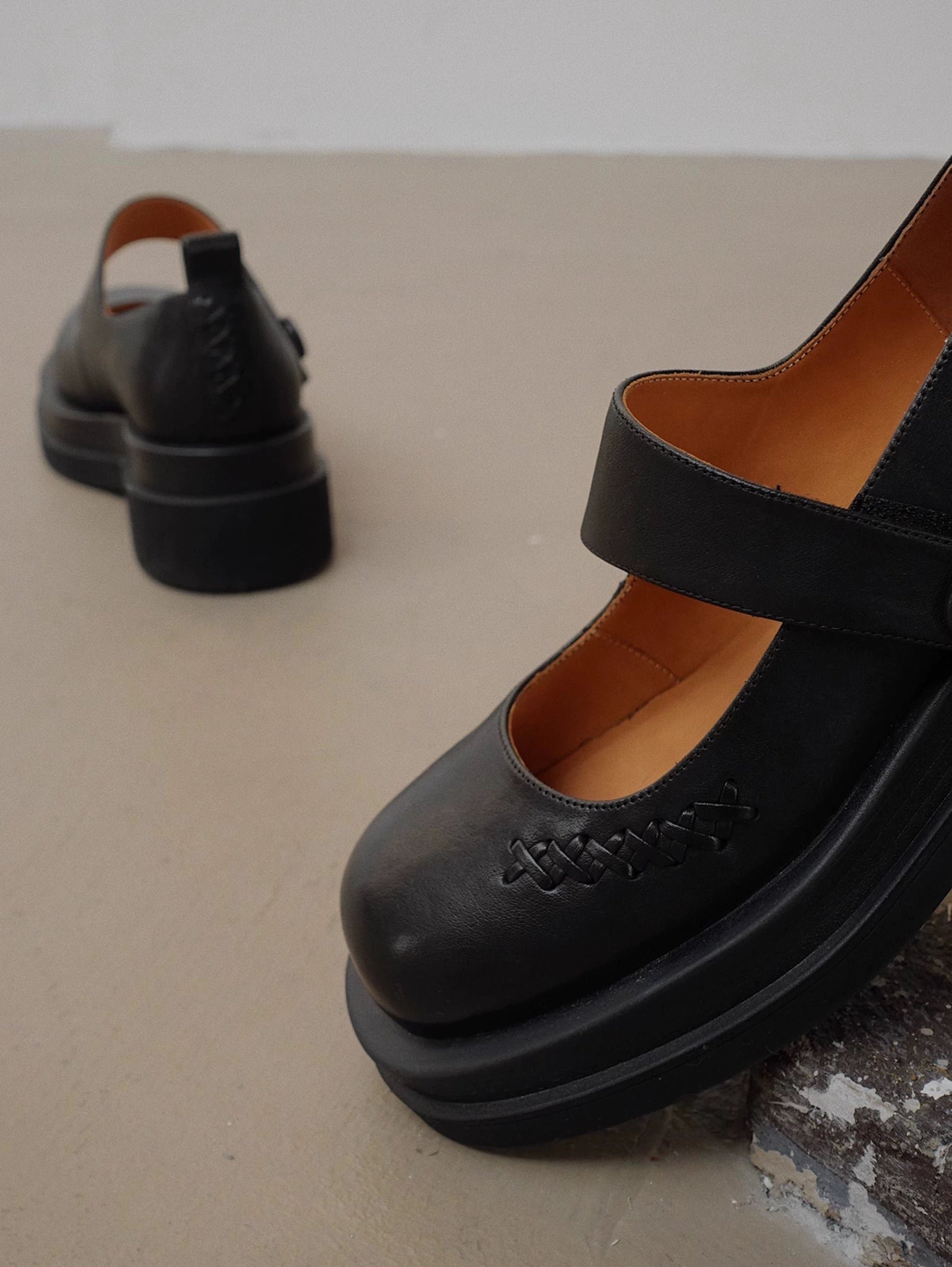 Showing the front details of a matte-finish black platform Mary Jane shoes with wide strap and low block heel, with stitching details at the front side