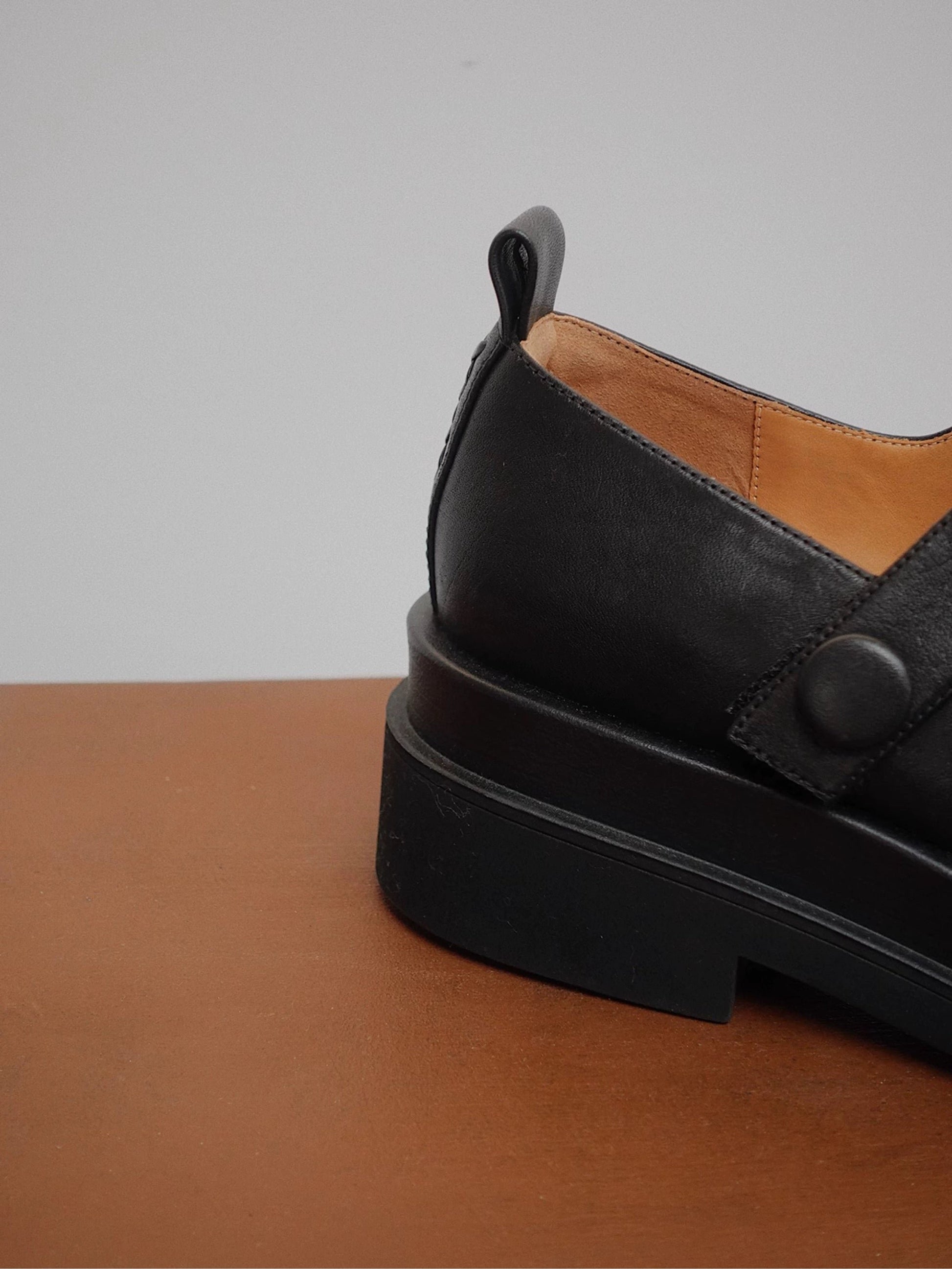 Showing the back details of a matte-finish black platform Mary Jane shoes with wide strap and low block heel