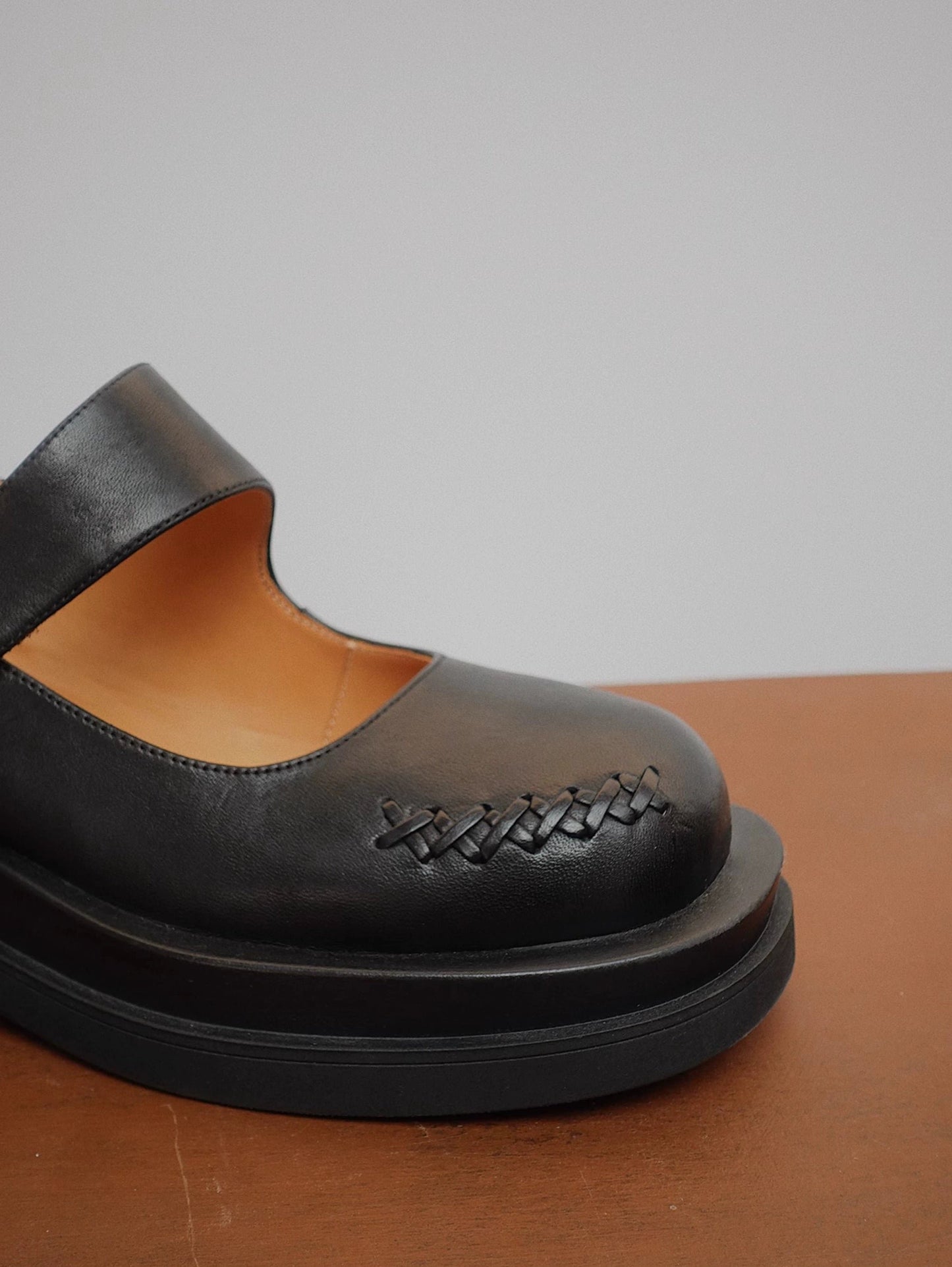 Showing the front details of a matte-finish black platform Mary Jane shoes with wide strap and low block heel, with stitching details at the front side