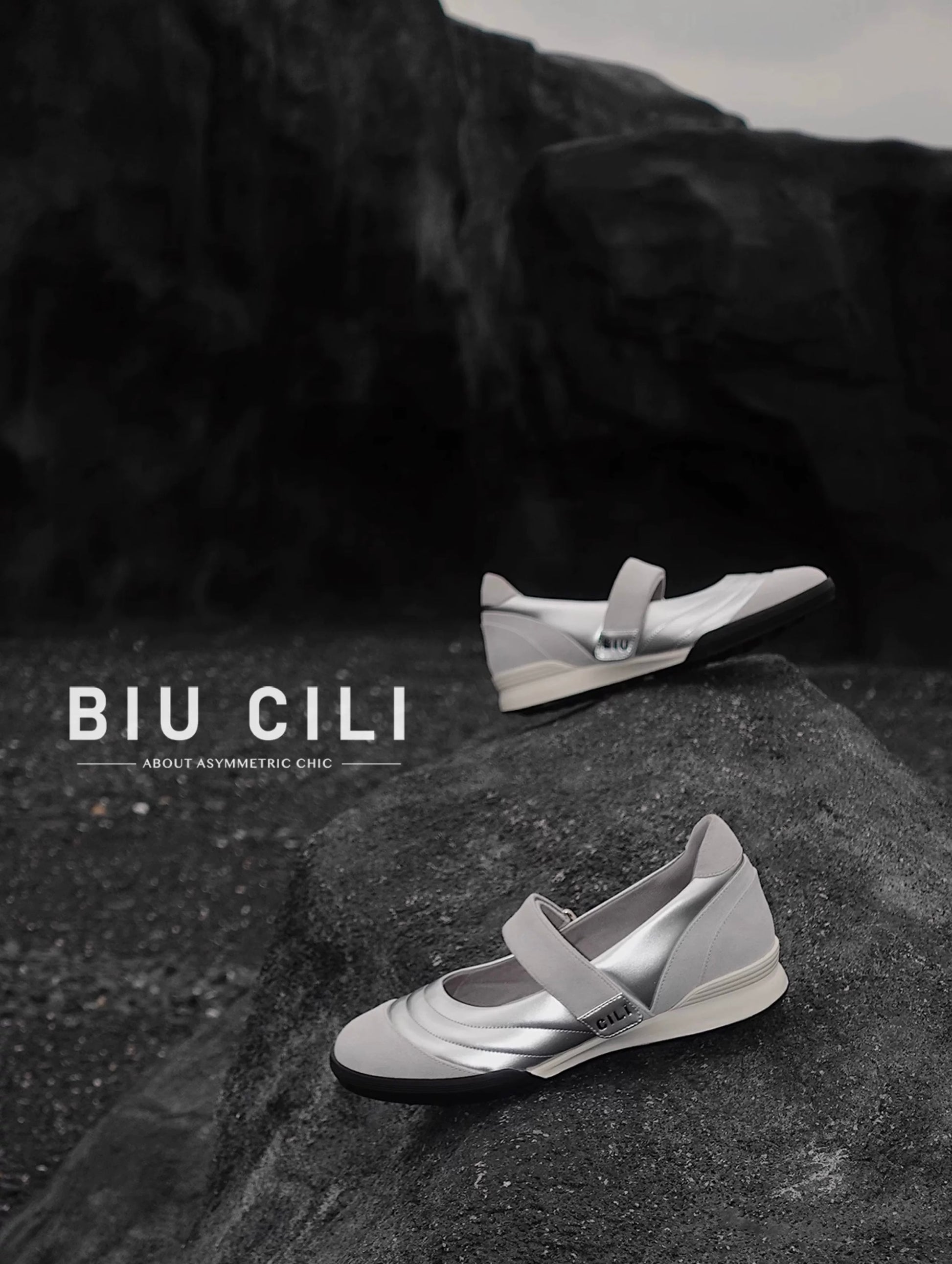 Pair of Kaia leather Mary Jane flats in colorblock white and silver positioned on a rough rock-like surface