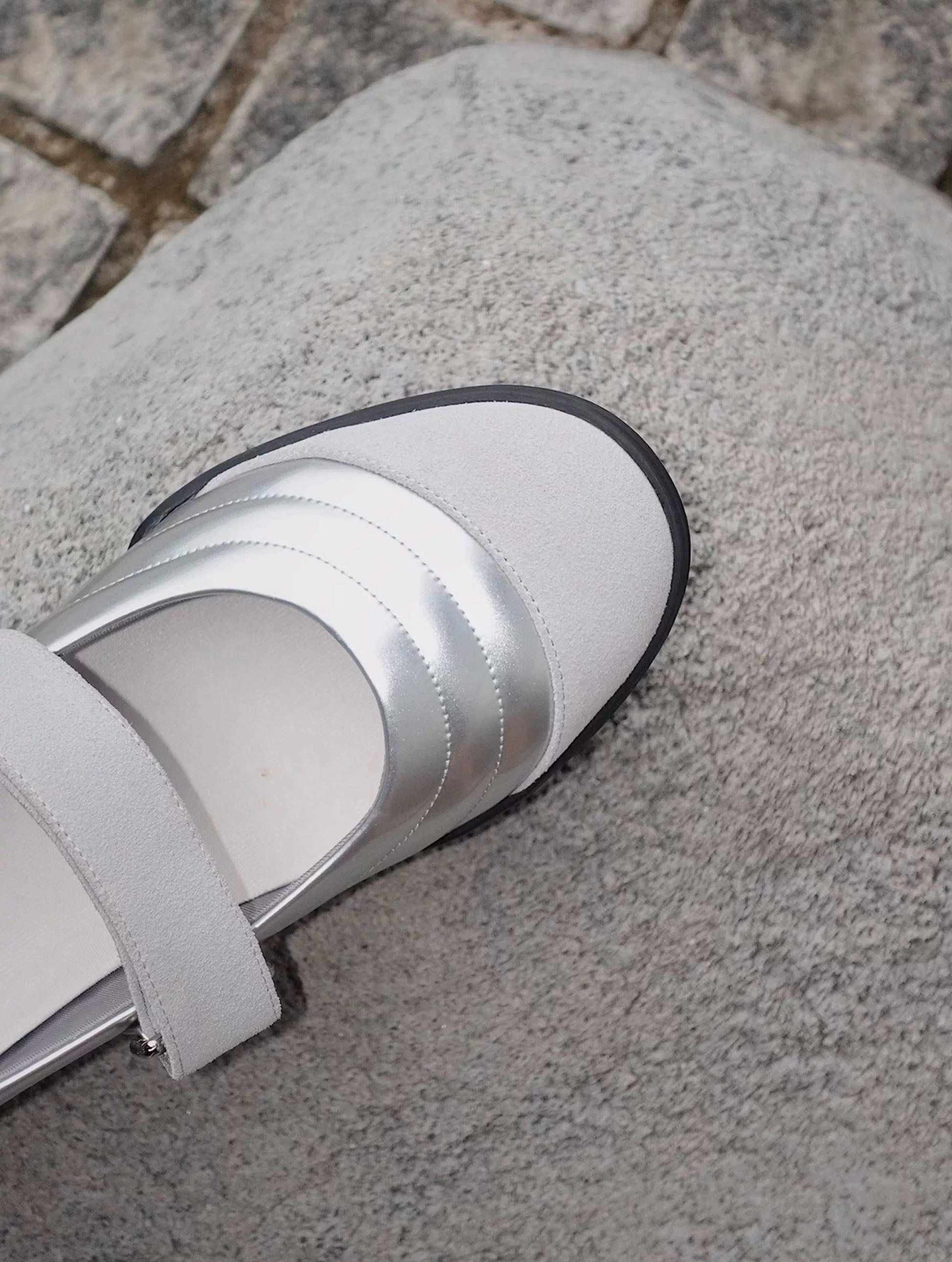 Close-up of Mary Jane flats in silver and white toe cap styles