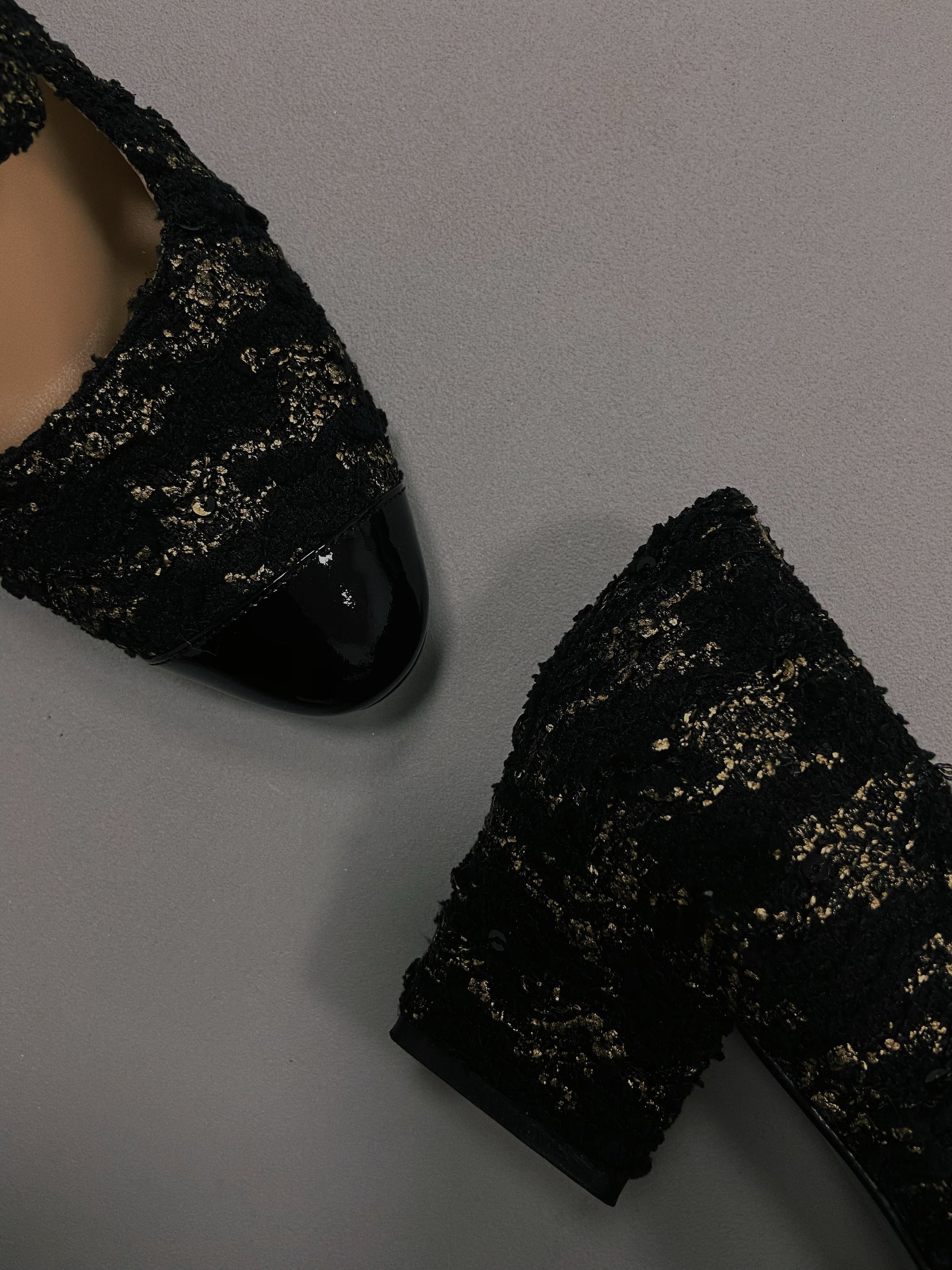 Elegant black Mary Janes featuring patent leather tweed design with asymmetric details and mid block heel