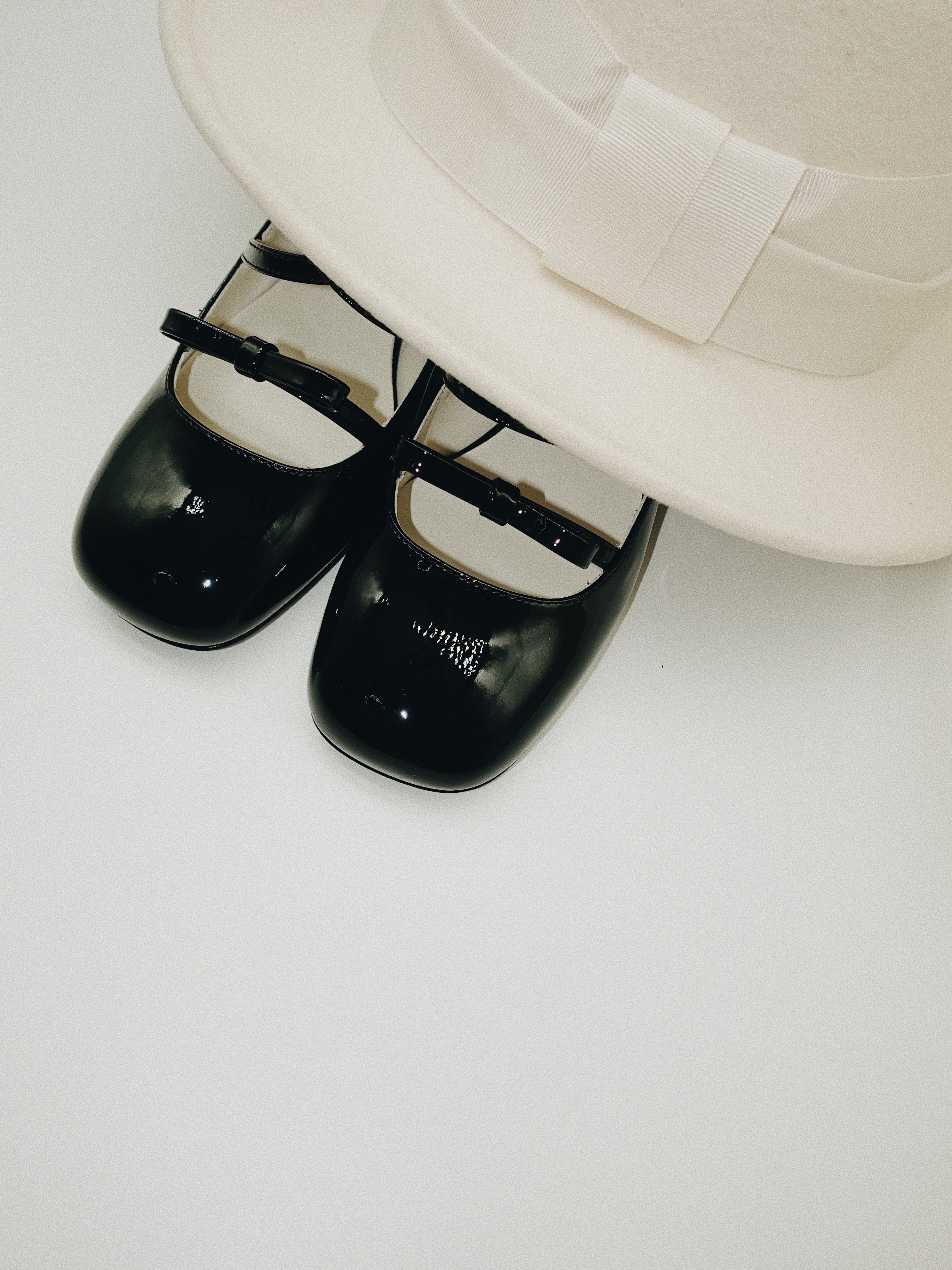 Black patent leather Mary Jane heels with triple straps, block heel, and bow detail.