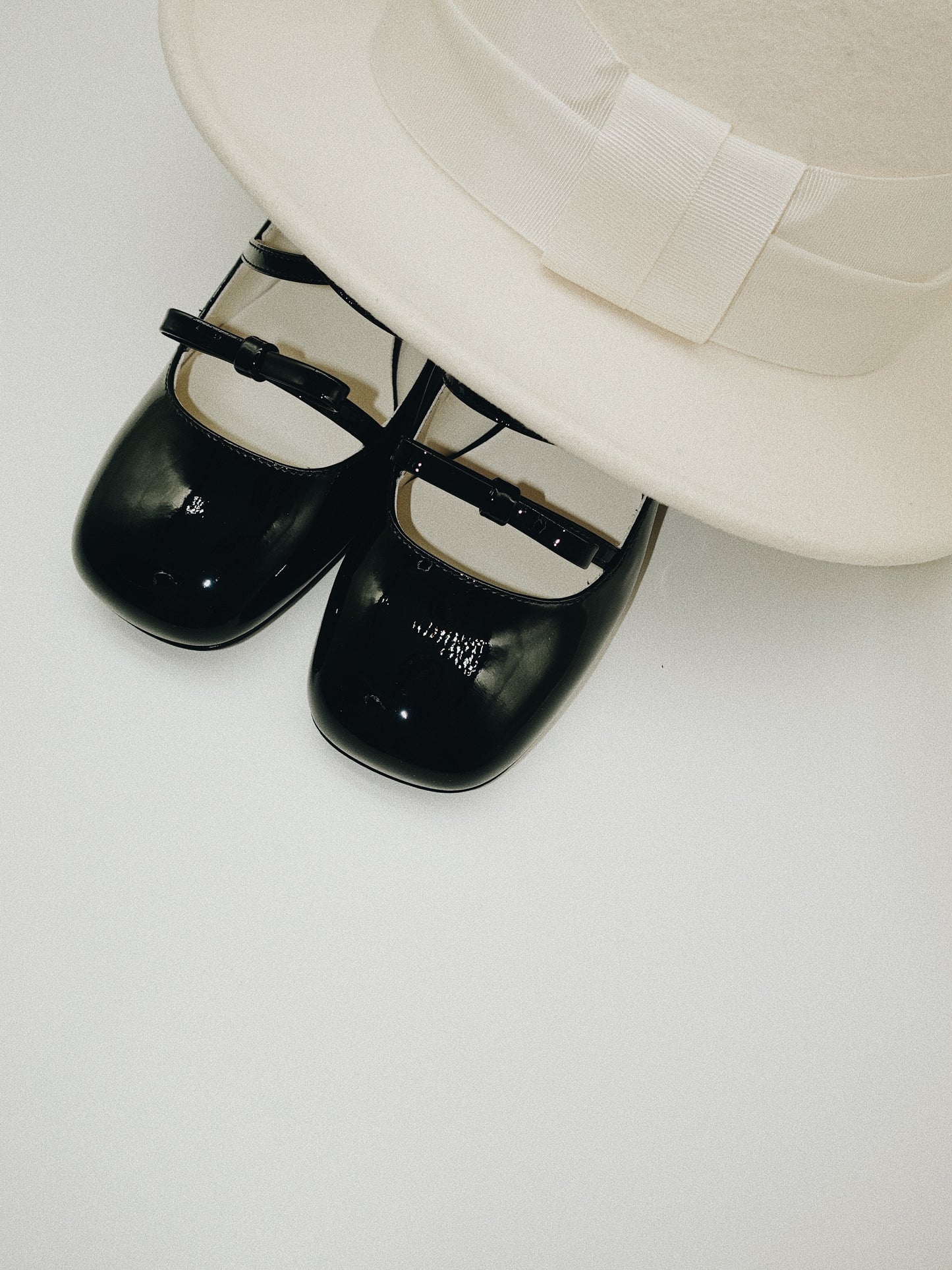 Black patent leather Mary Jane heels with triple straps, block heel, and bow detail.