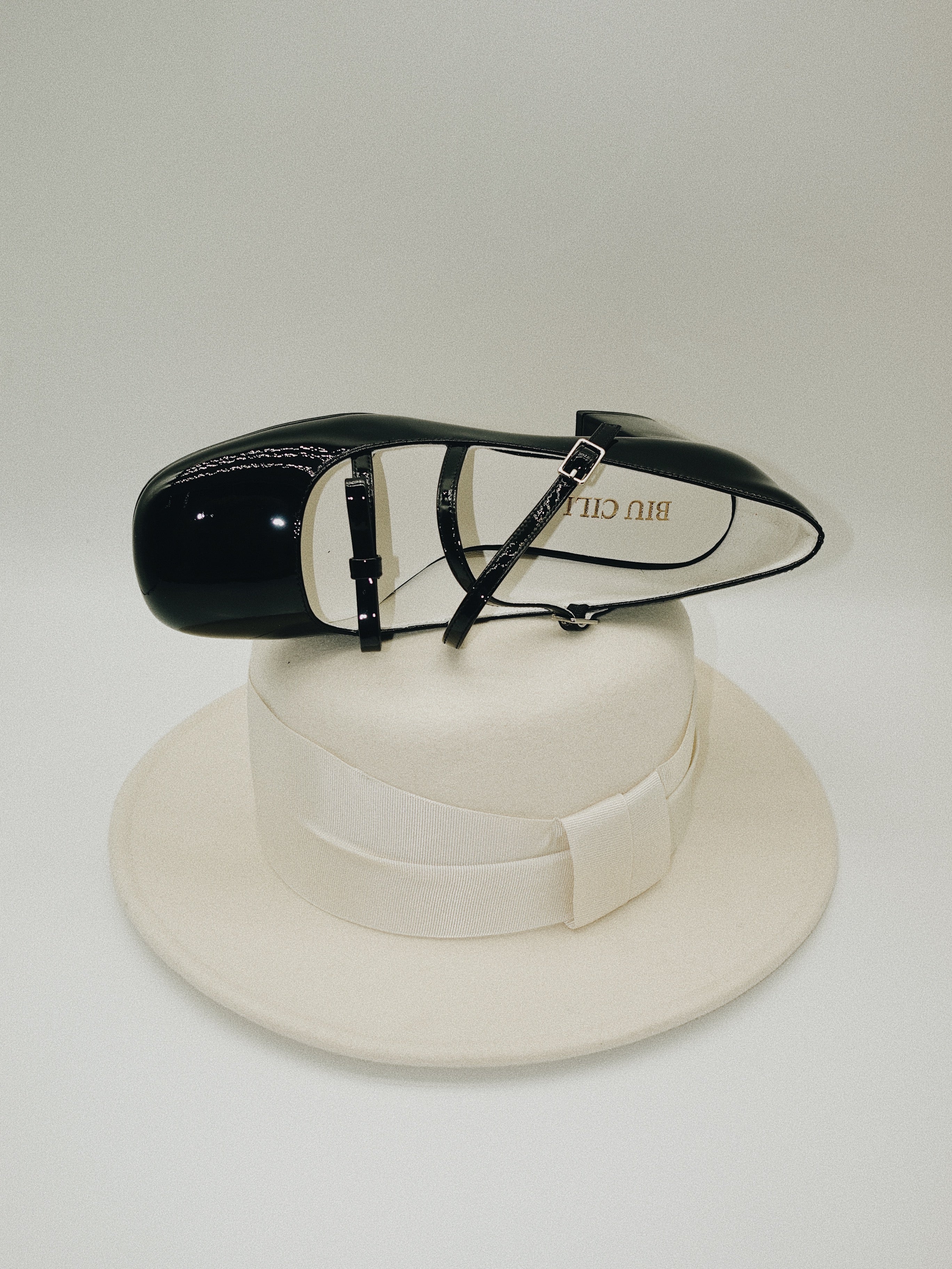 Black patent leather Mary Jane heels with triple straps, block heel, and bow detail.