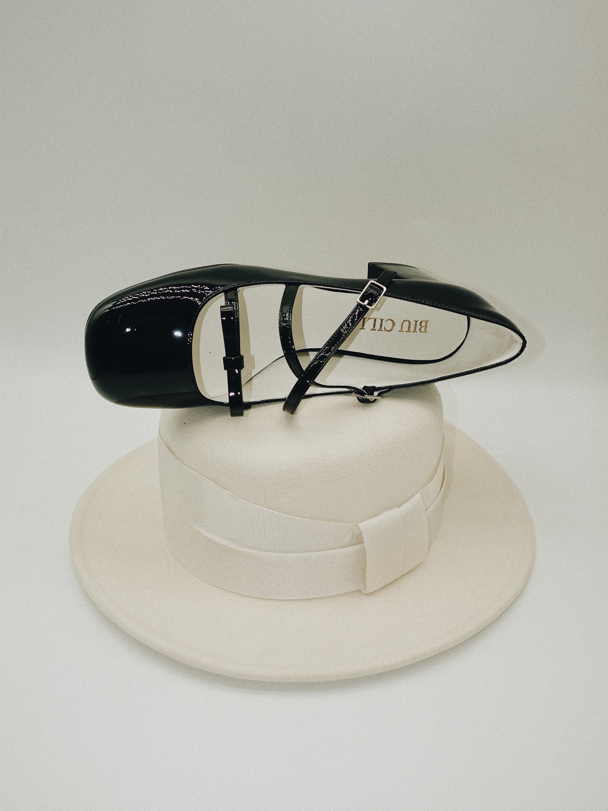 Black patent leather Mary Jane heels with triple straps, block heel, and bow detail.