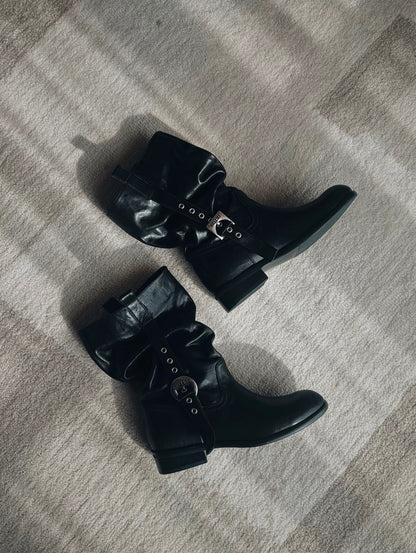 Pair of black leather boots with buckles on a carpet