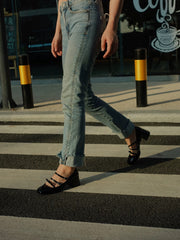 Women wearing a pair of black patent leather Mary Jane heels with triple straps, block heel, and bow detail, crossing the street