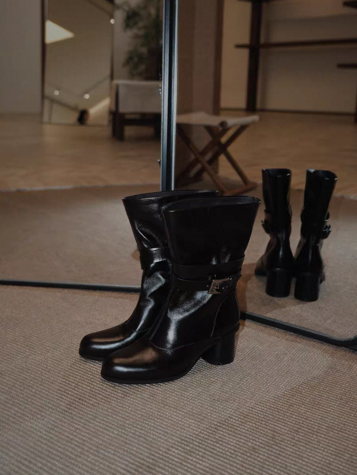 Black leather boots on a textured surface with a blurred indoor background