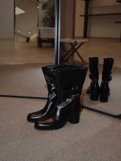 Black leather boots on a textured surface with a blurred indoor background
