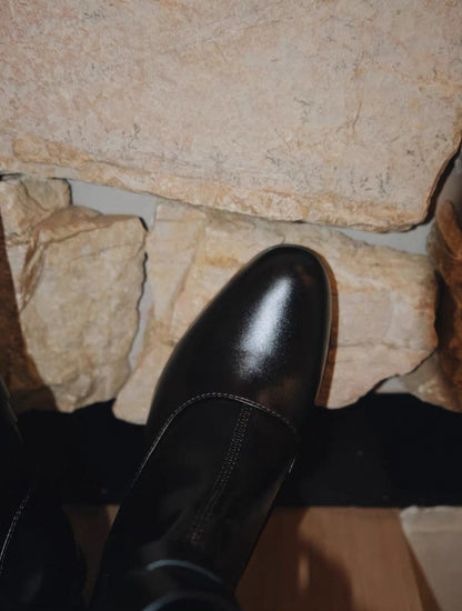 Black leather boot on a stone floor