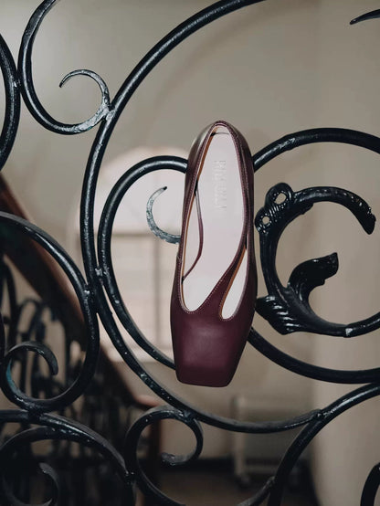 Maroon high-heeled shoe on a decorative metal railing