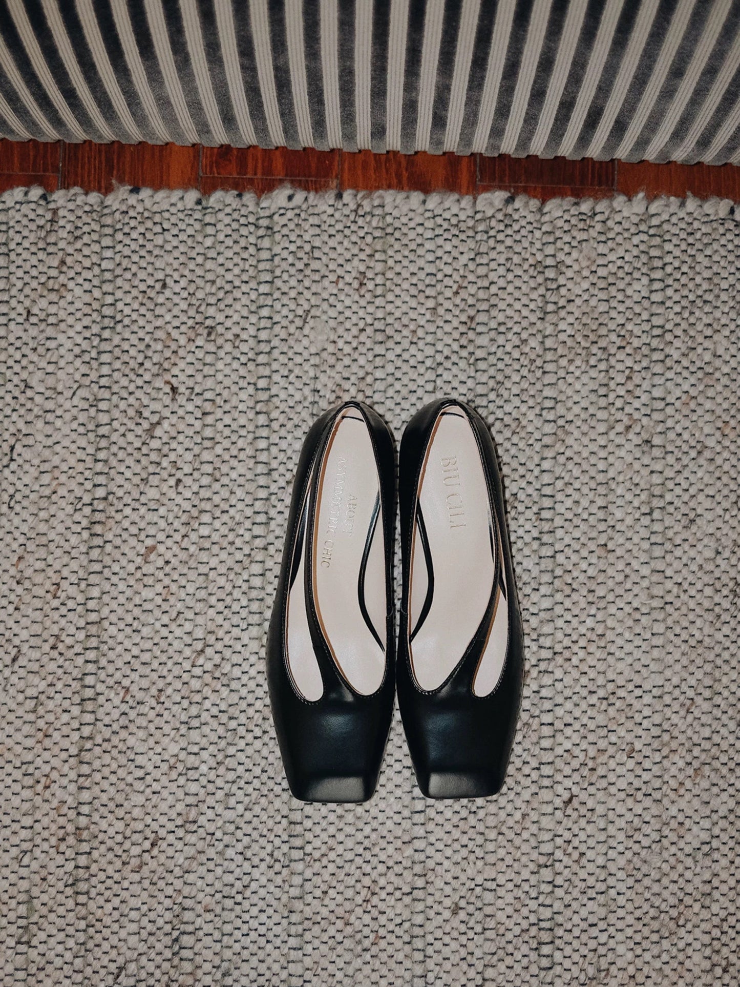 Black leather shoes with cut-out on a textured carpet