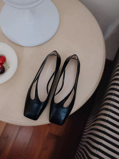 Black high-heeled shoes on a round beige table with a blurred background