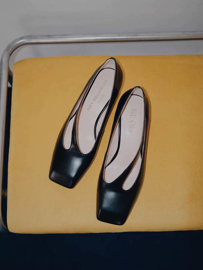 Black shoes with white soles on a yellow cushion