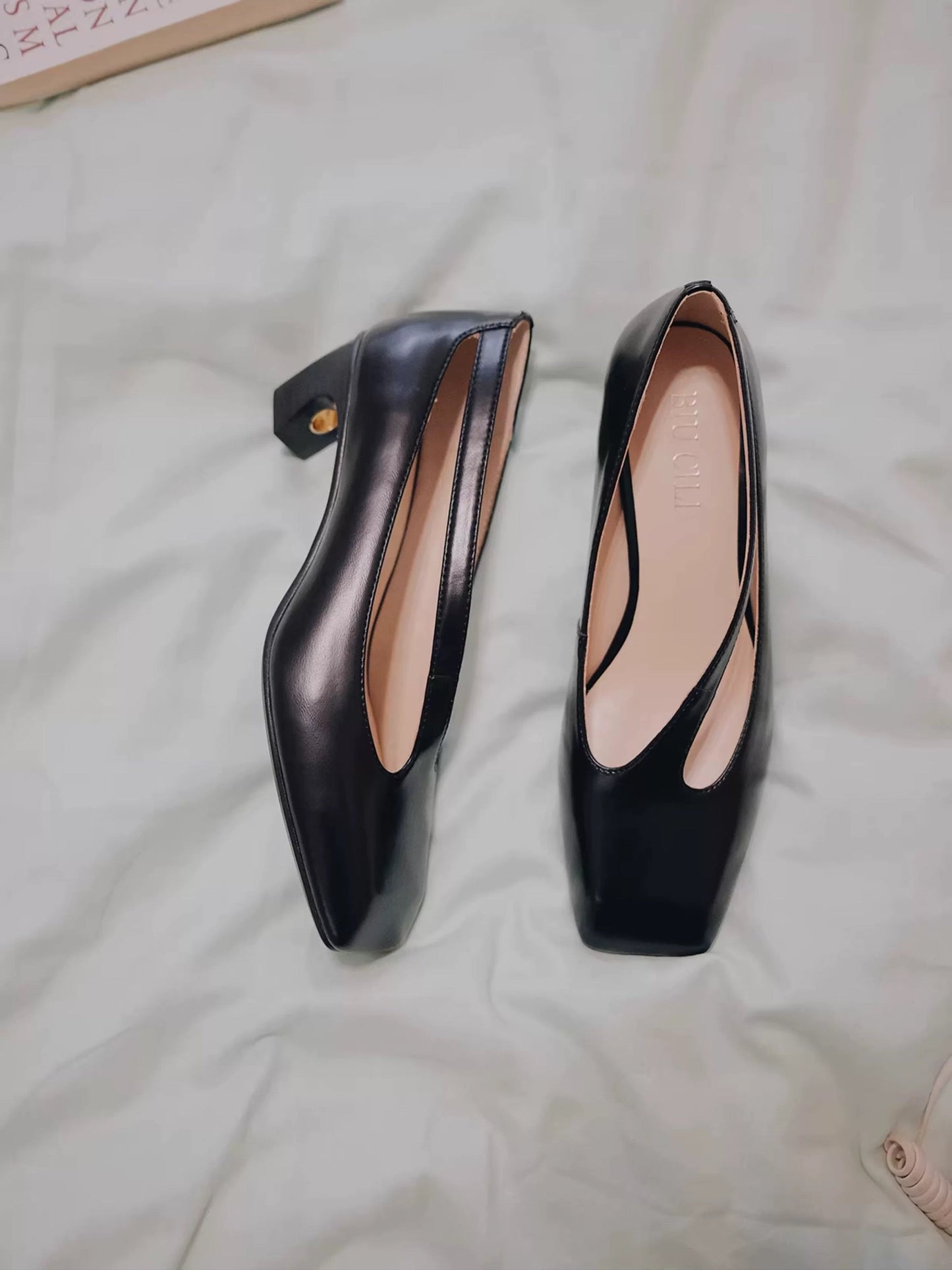 Pair of black high-heeled shoes on a light-colored fabric surface