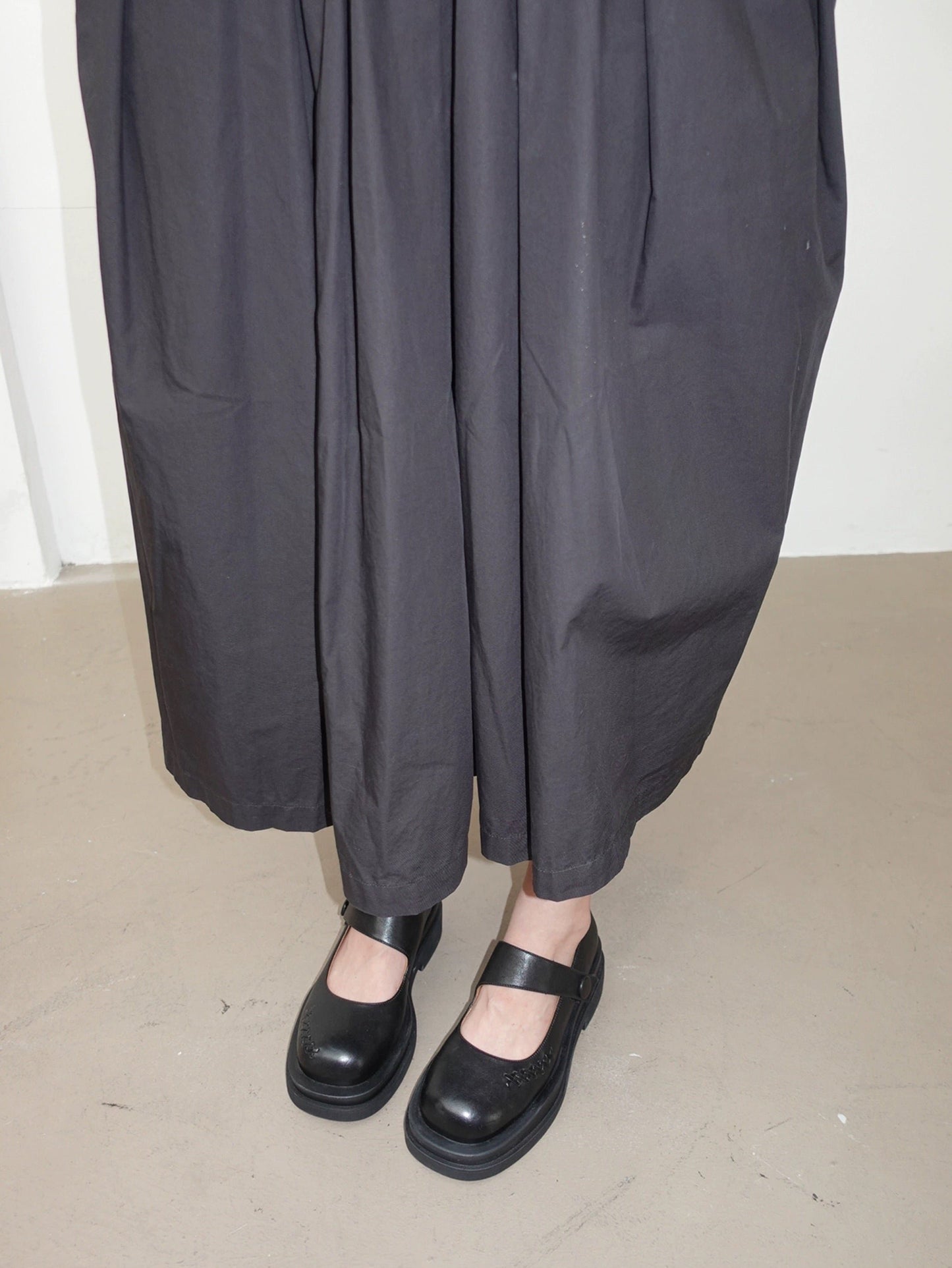 Women wearing a pair of matte finish black platform Mary Jane shoes with wide straps and low block heels