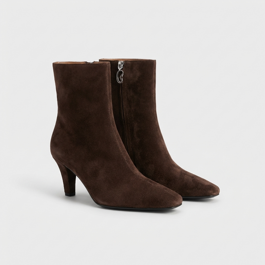 Pair of brown suede ankle boots on a light gray background
