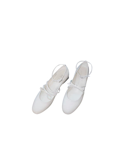White patent leather Mary Jane heels with asymmetric bow straps