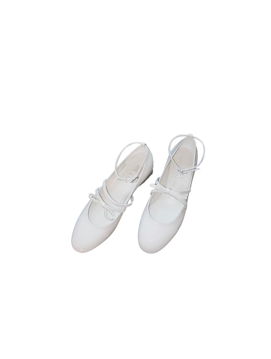 White patent leather Mary Jane heels with asymmetric bow straps